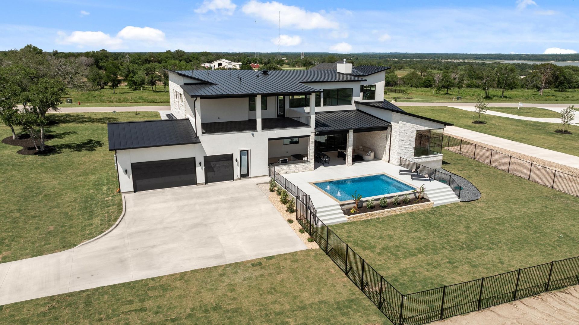 Modern two-story gray house with a pool, fenced yard, and wide driveway in a suburban setting