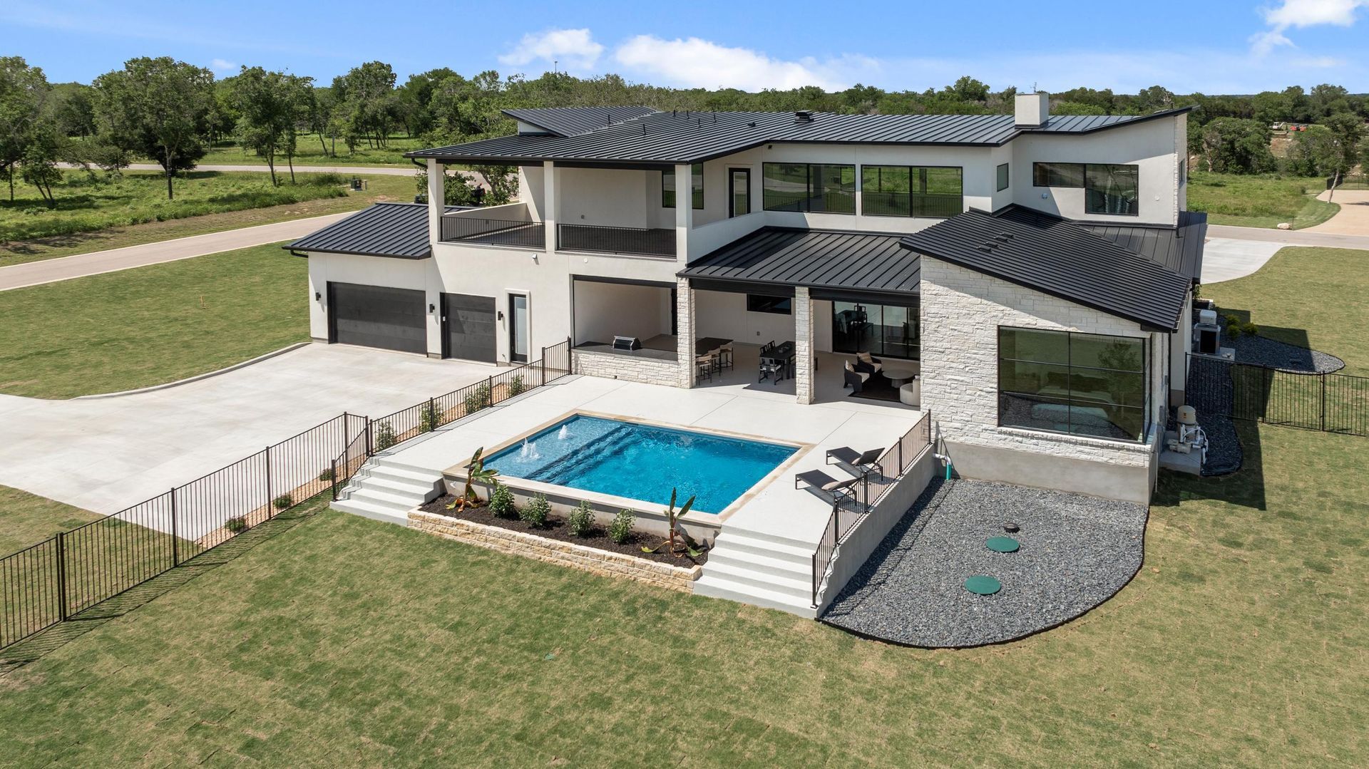 Modern two-story house with a swimming pool, patio, and landscaped yard in a sunny setting