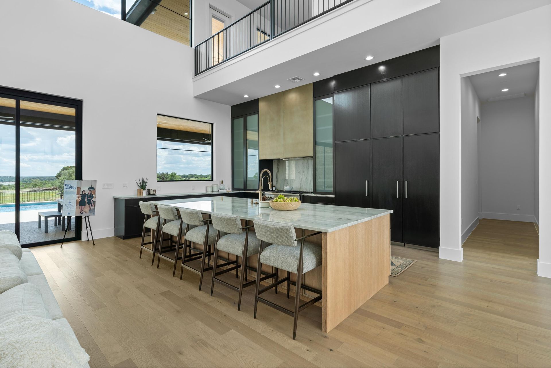 Modern open-plan kitchen and dining area with island seating, light wood floors, and large windows