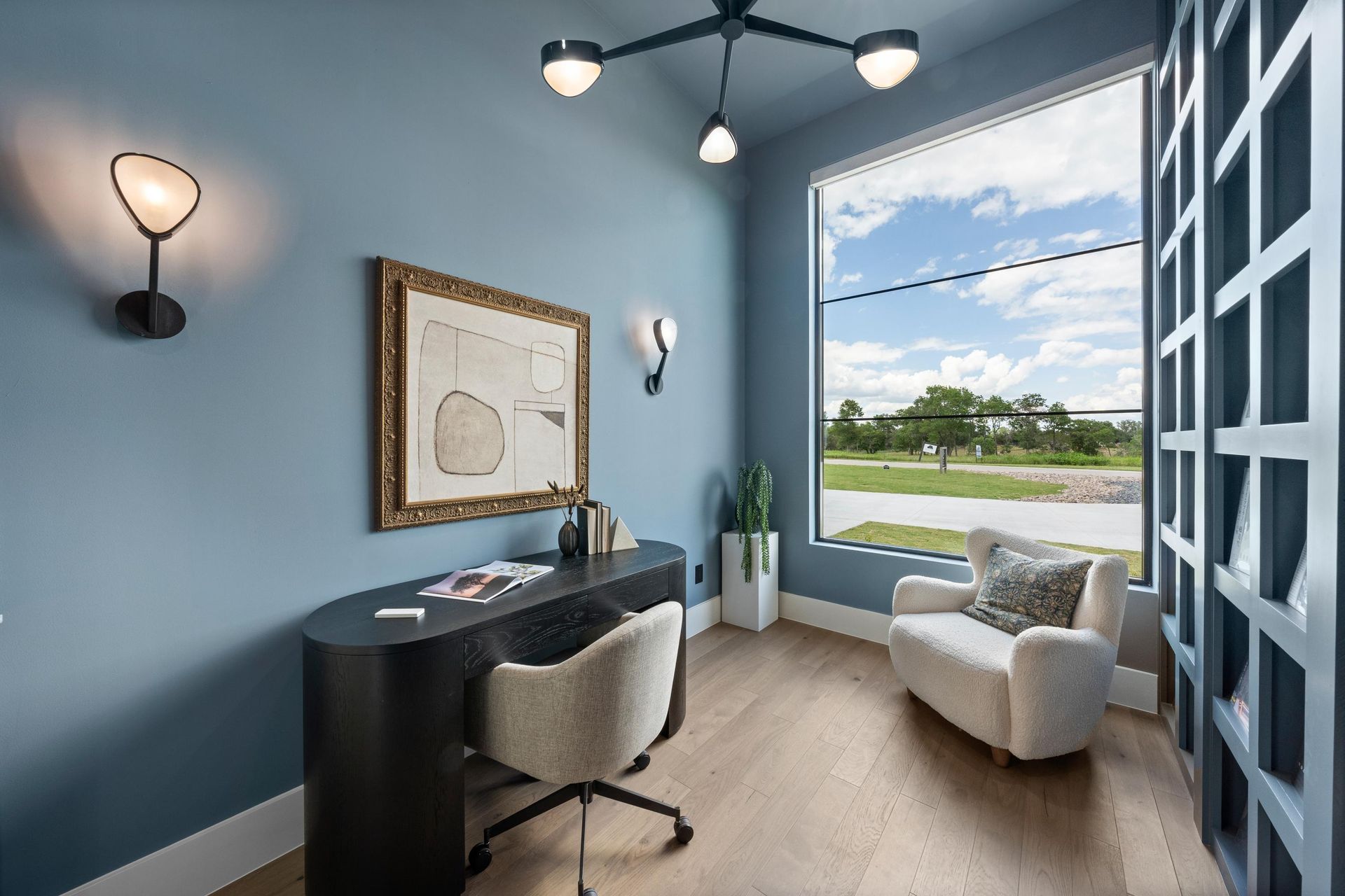 Modern home office with blue walls, desk, chair, armchair, and large window view