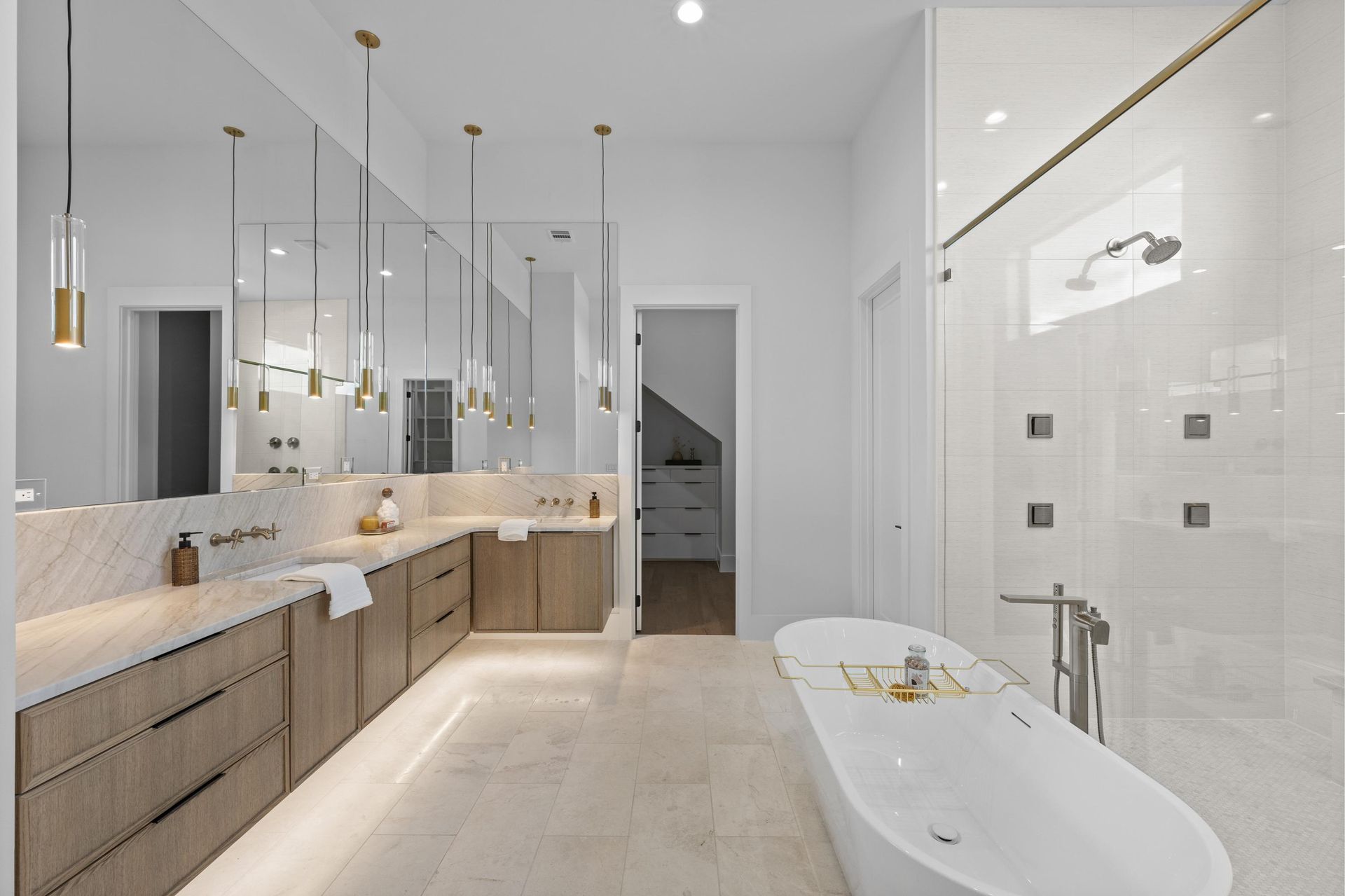 Bright modern bathroom with double vanity, large mirrors, glass shower, and freestanding tub
