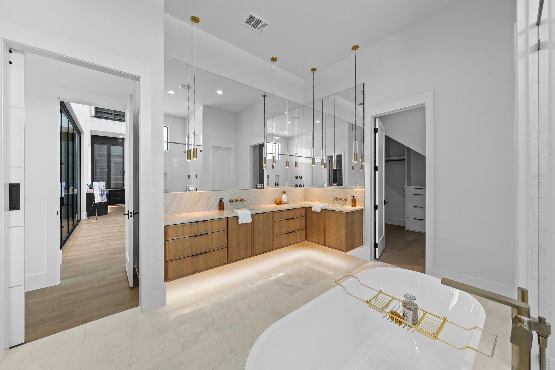 Bright modern bathroom with double vanity, large mirror, glass shower, and freestanding tub