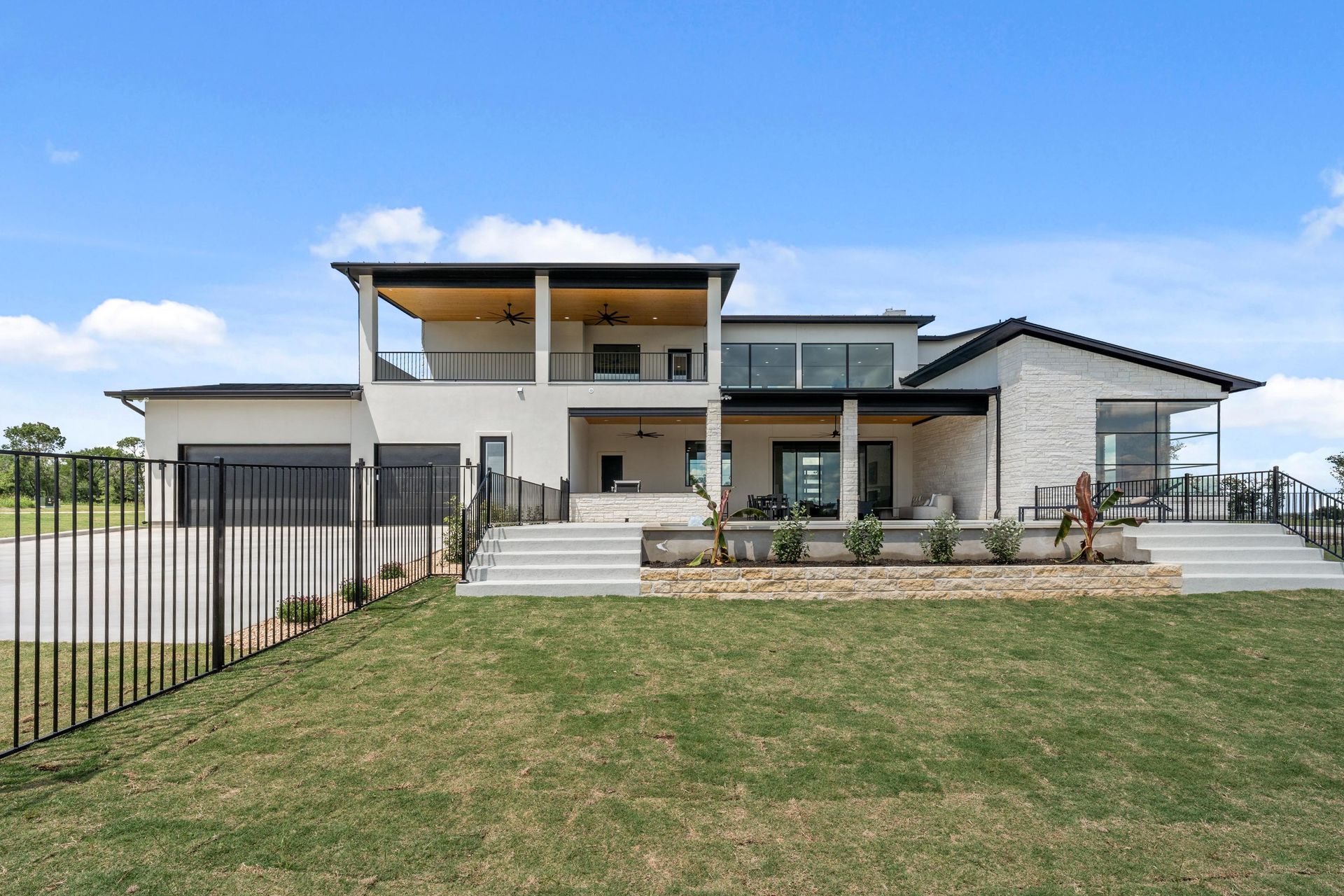 Modern two-story house with a large lawn, patio, and blue sky