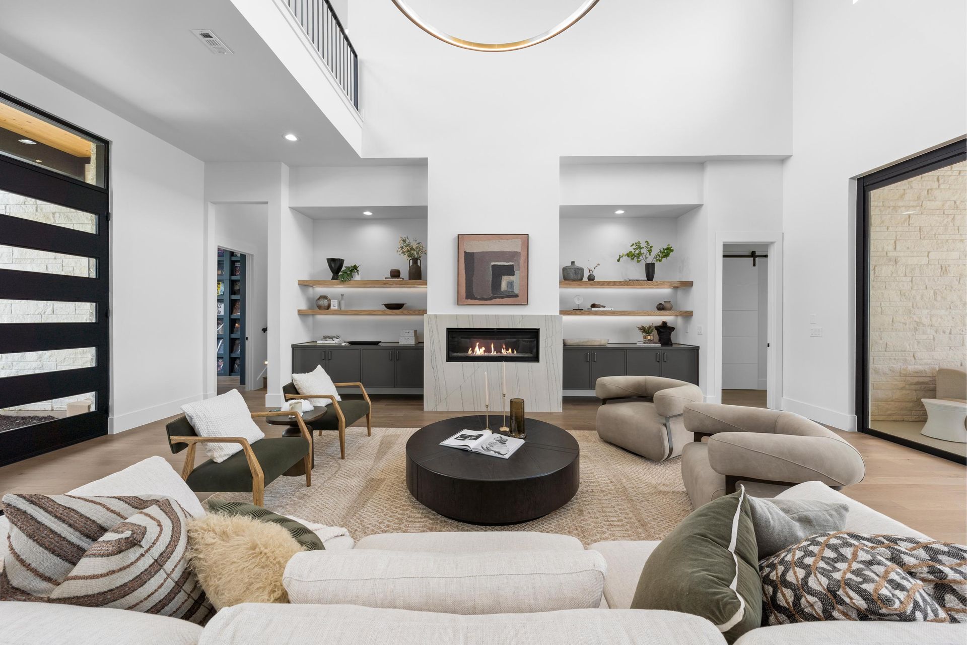 Modern living room with white walls, beige seating, fireplace, and built-in shelves with plants and decor