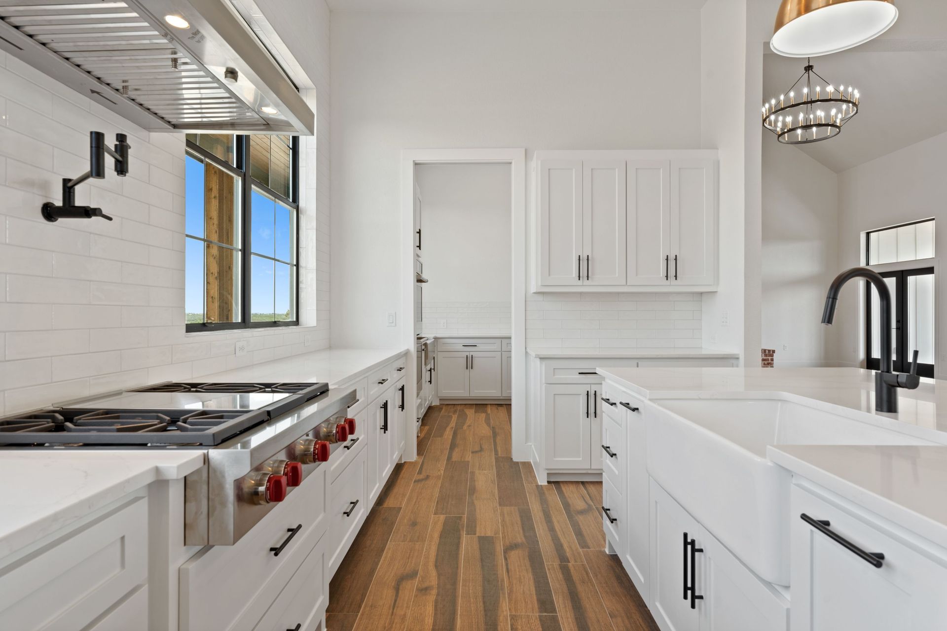 Bright white modern kitchen with wood floors, black fixtures, and a large island.