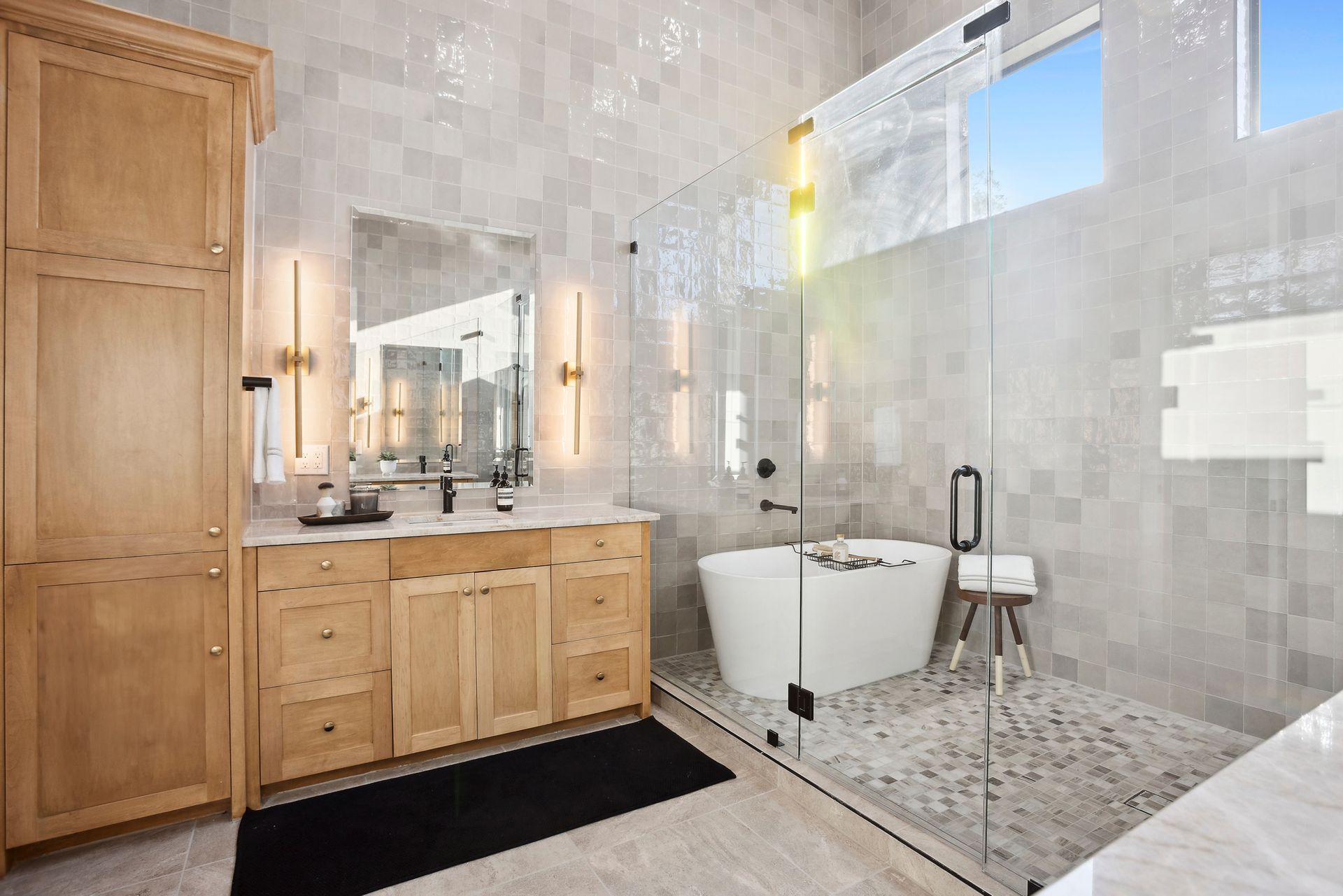 Modern bathroom with double vanity, large mirror, freestanding tub, and tiled walls