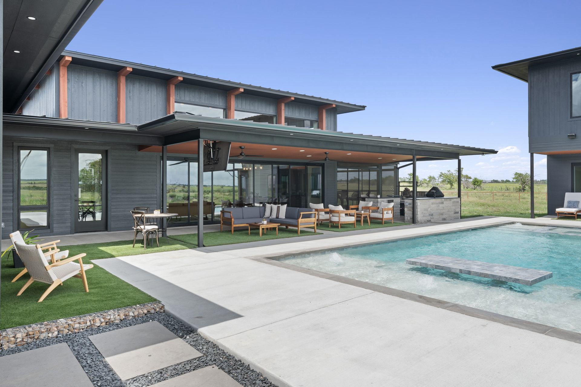 Modern house with patio and pool beside a concrete deck under a clear sky