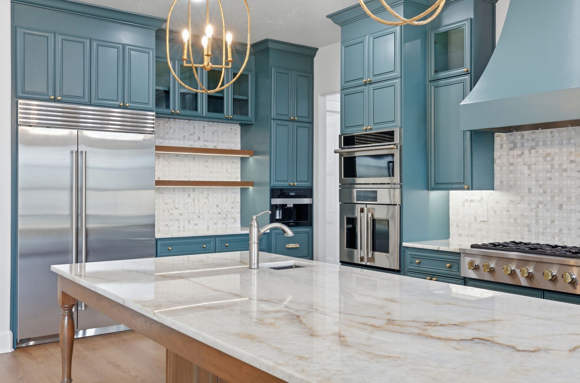 Modern kitchen with blue cabinets, stainless steel appliances, marble island, and pendant lights