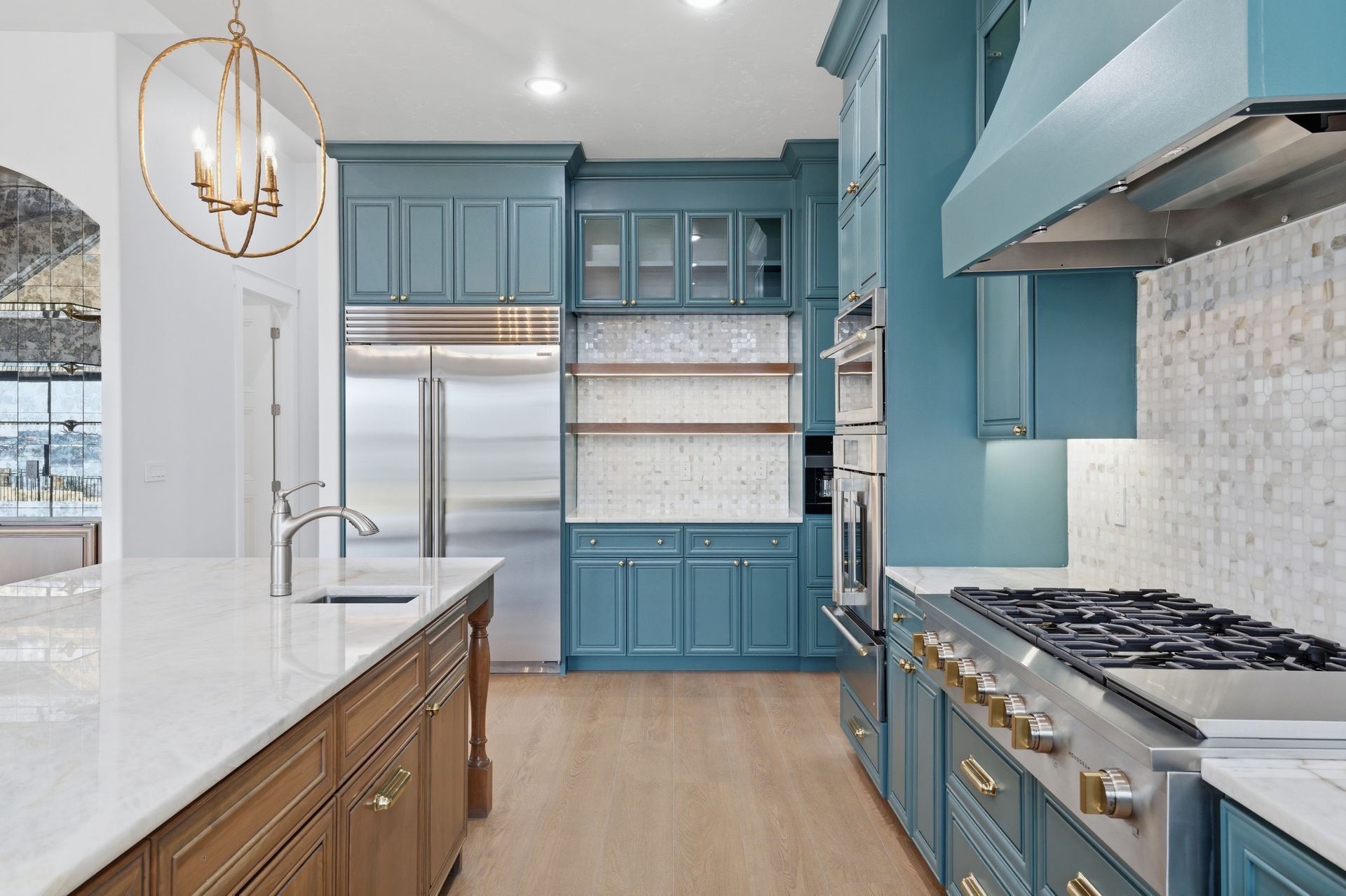 Bright blue-and-white modern kitchen with island, stainless appliances, and gas range
