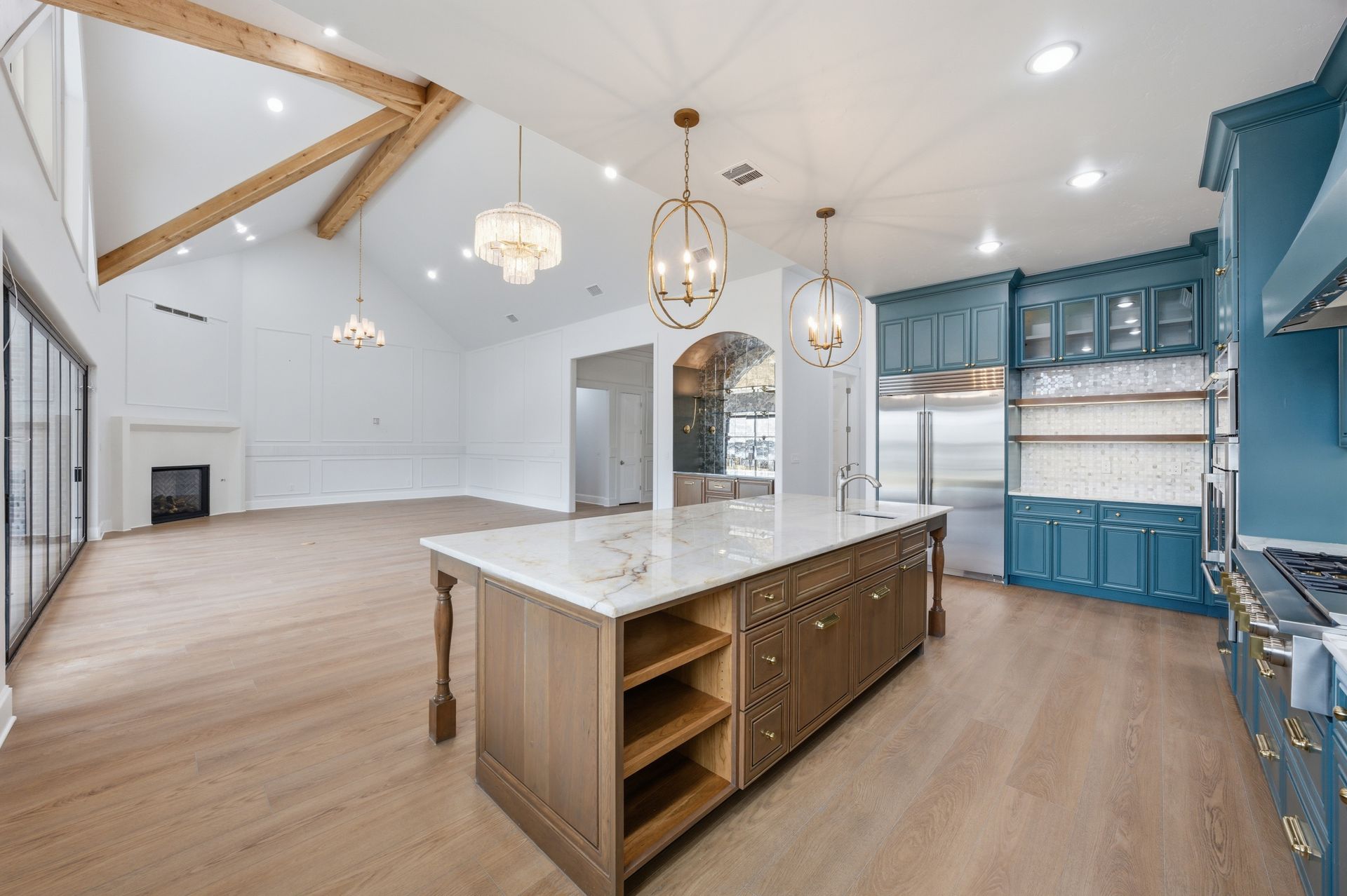 Bright white kitchen with large island, wood floors, vaulted ceiling, and blue cabinets