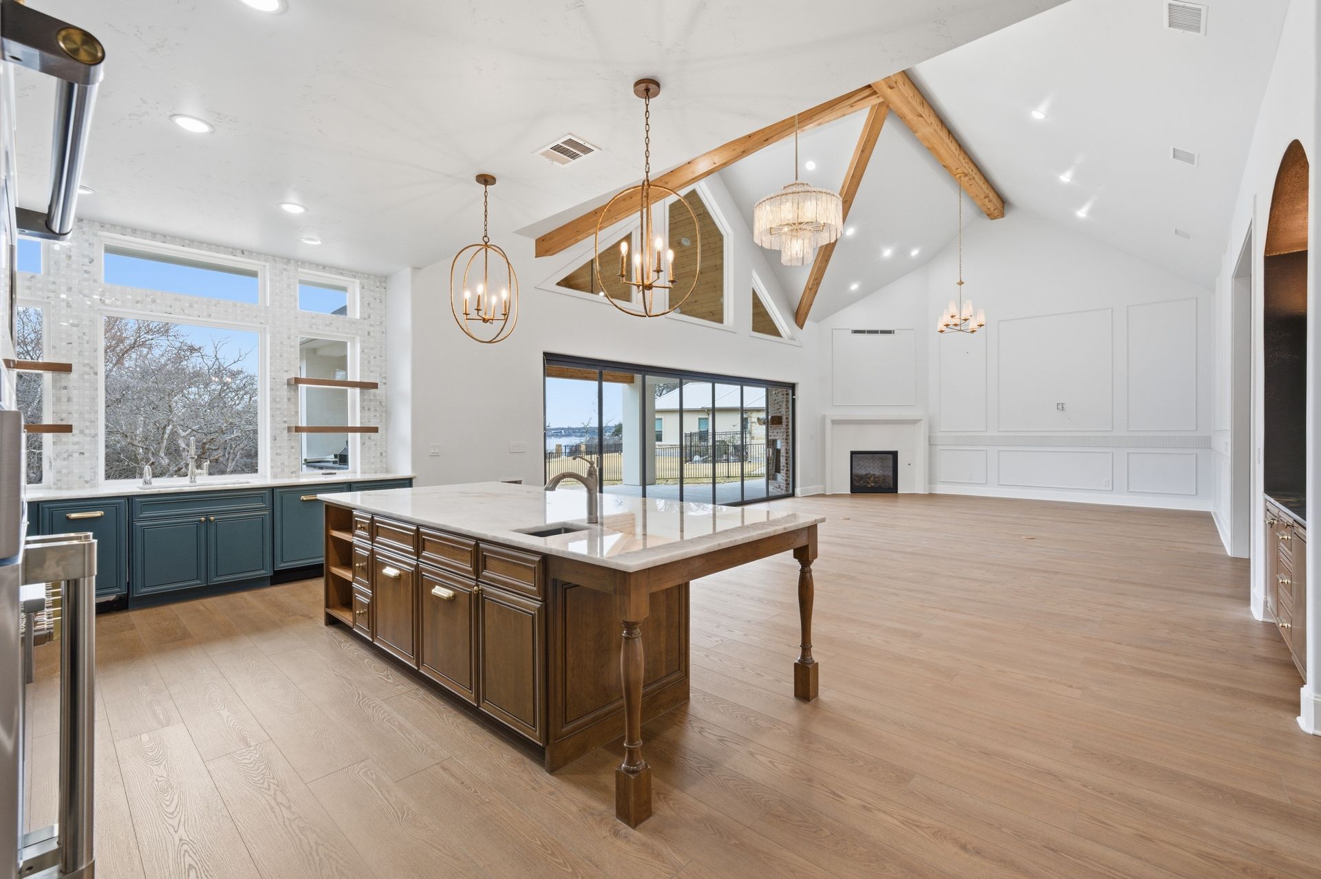Bright modern kitchen and living space with wood beams, island, blue cabinets, and large windows