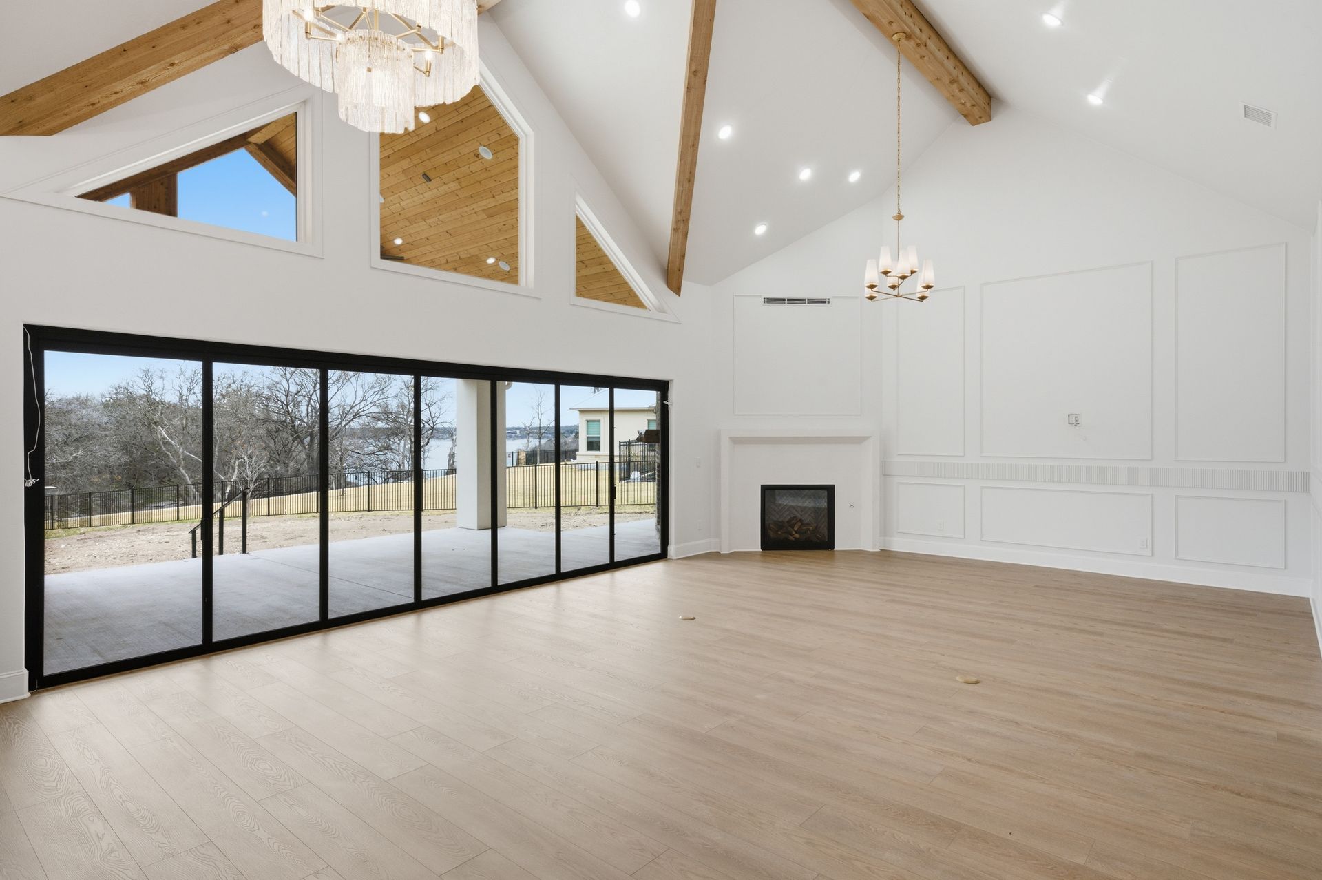 Spacious modern living room with vaulted ceilings, black sliding doors, fireplace, and light wood floors