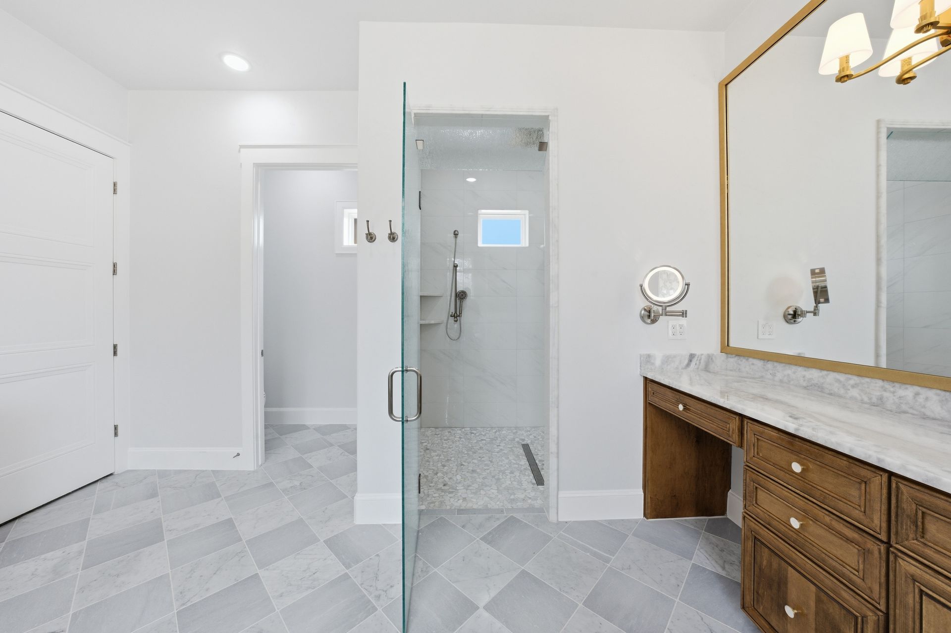Modern bathroom with glass shower, vanity, and light gray tile floors.