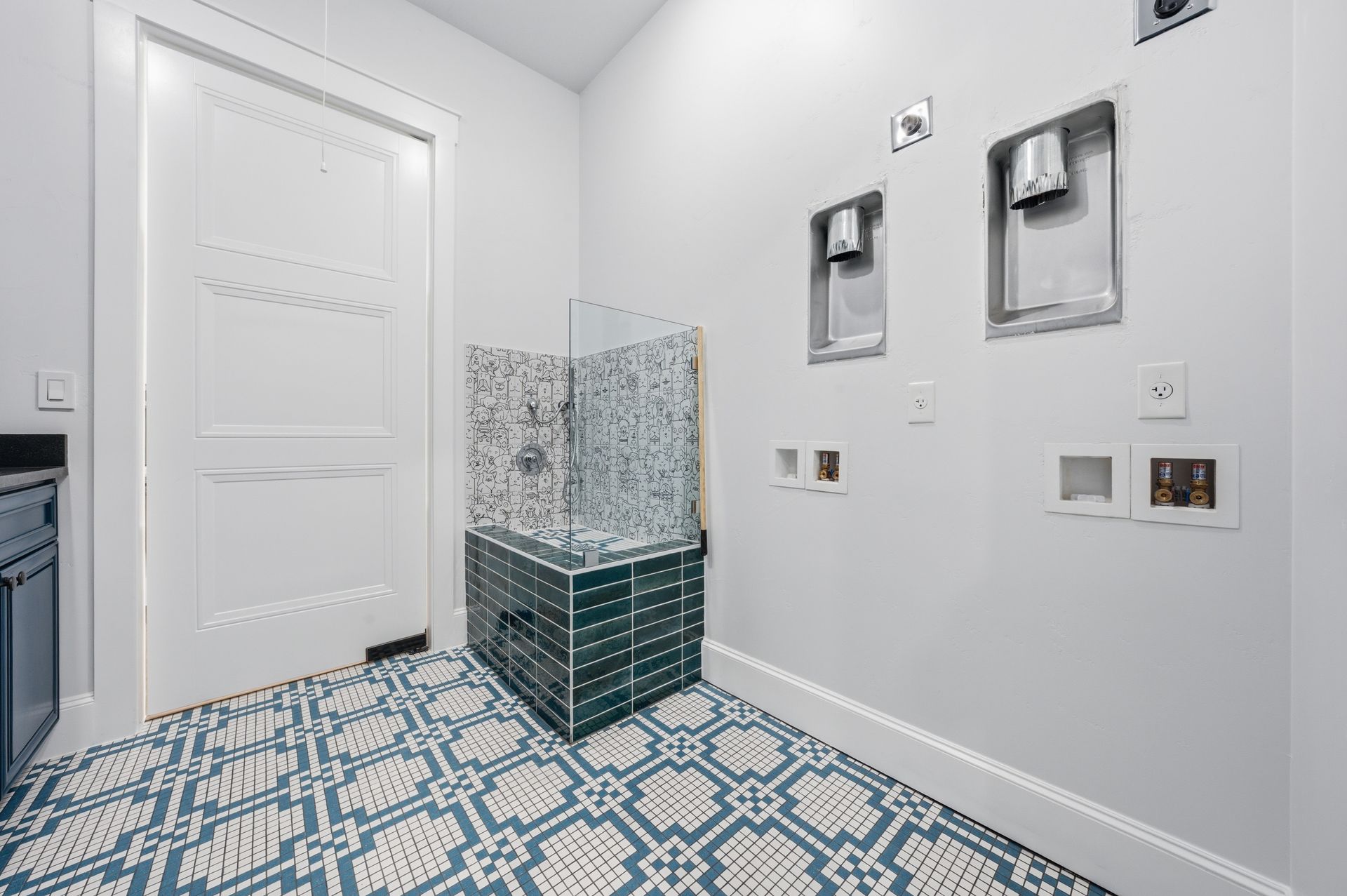 Bright bathroom with blue patterned tile, white walls, and a green-tiled shower bench.