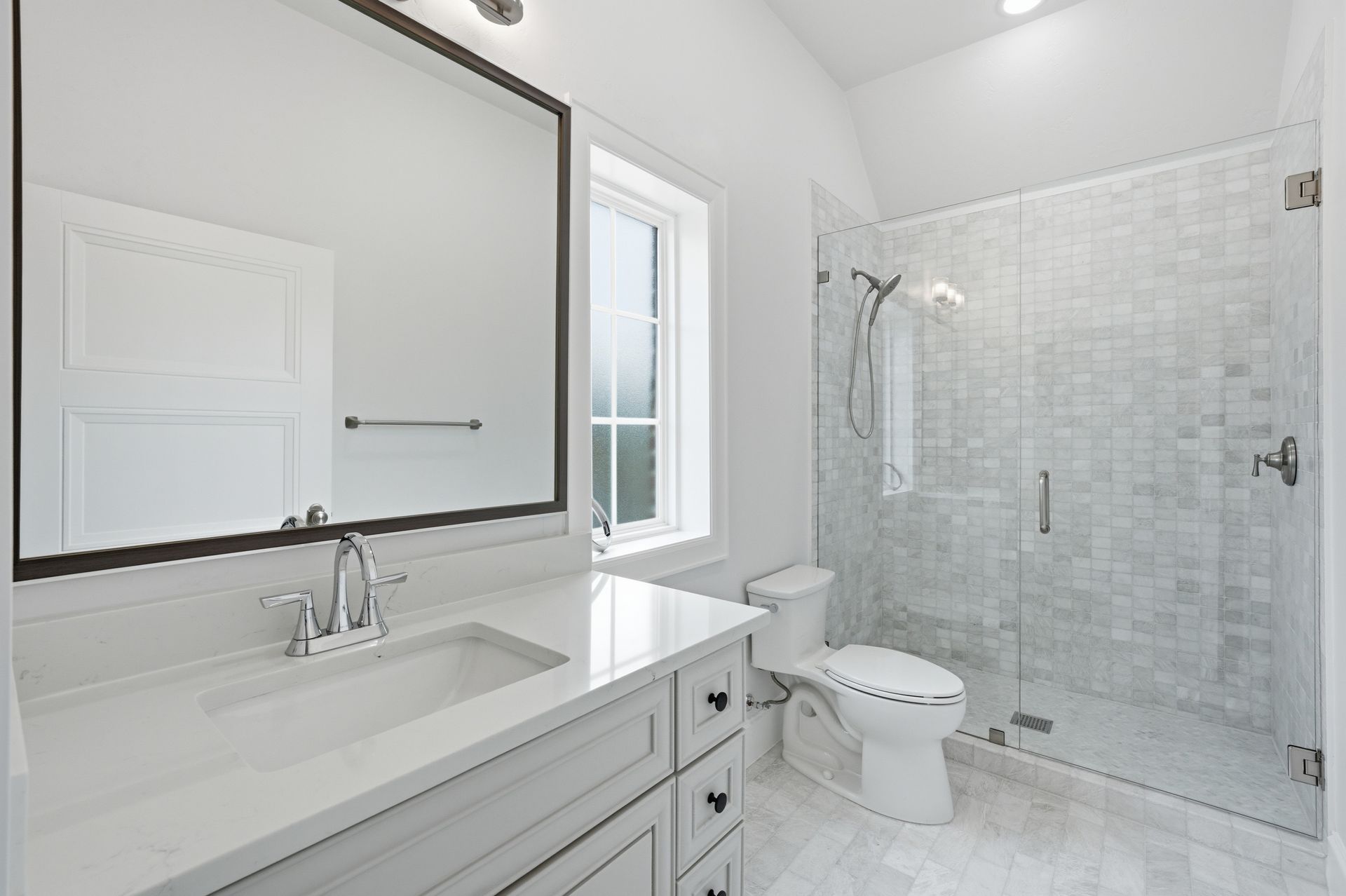 Bright white bathroom with vanity, mirror, toilet, and glass shower