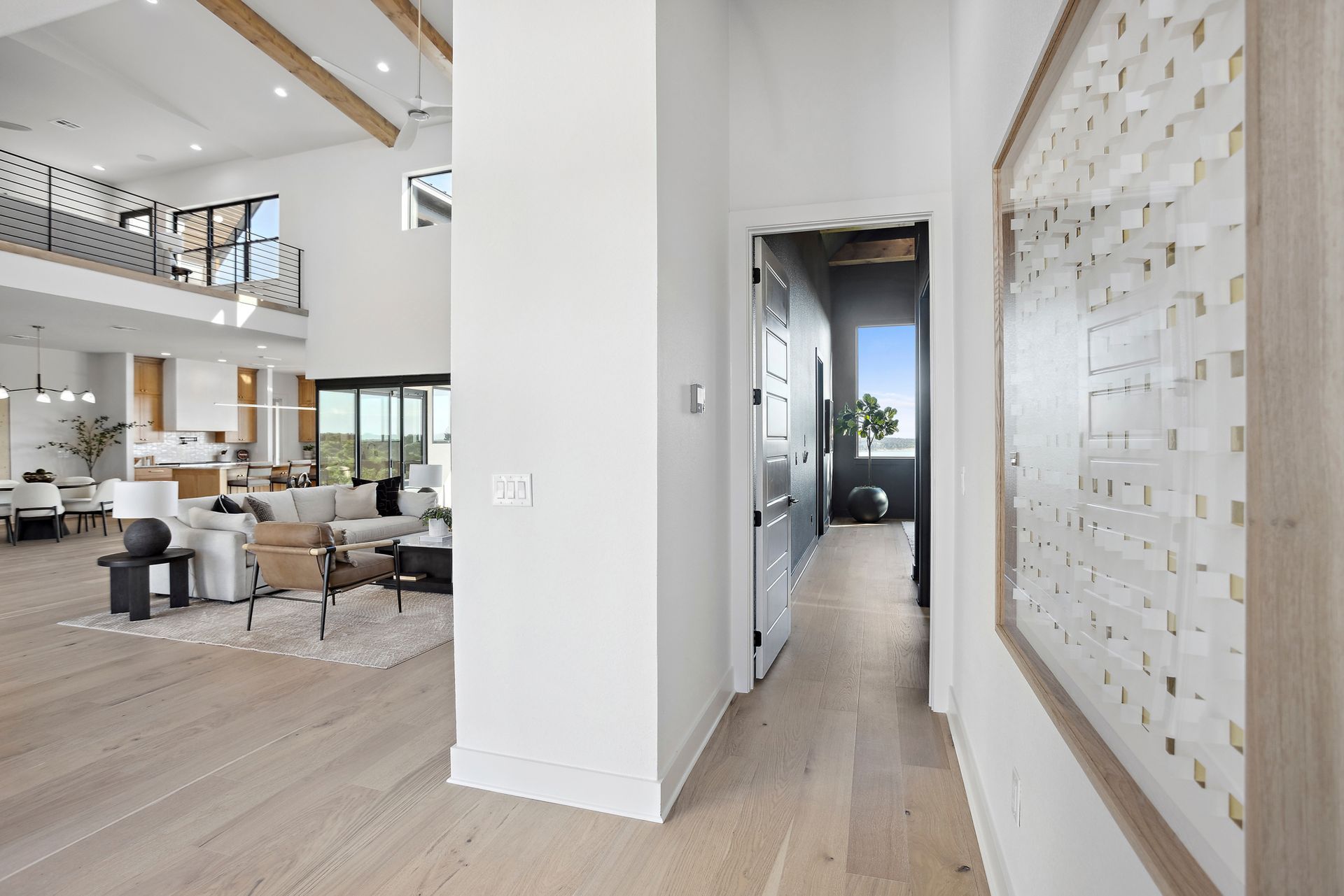 Modern open-concept living room and hallway with light wood floors and white walls