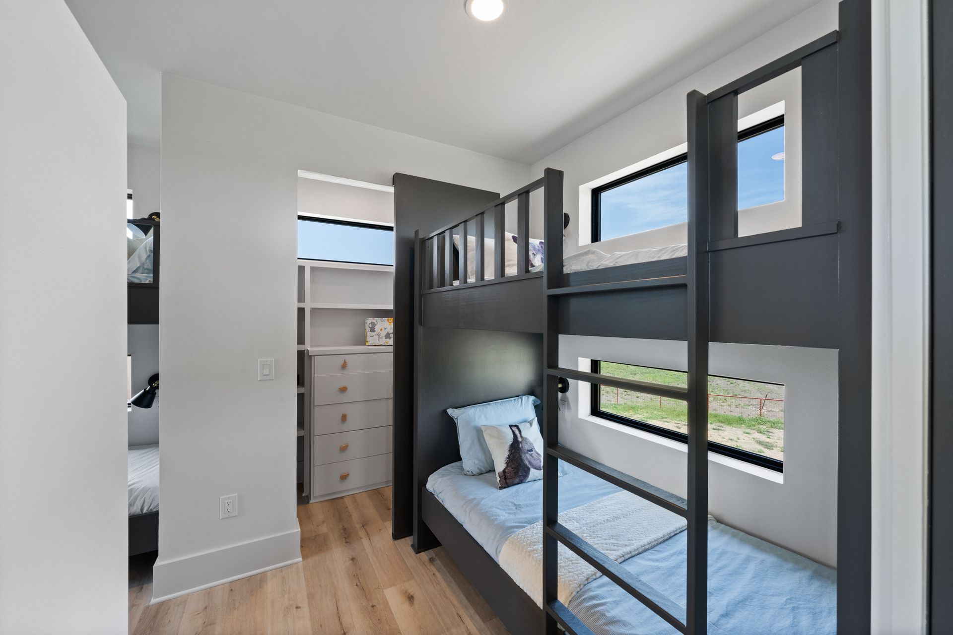 Modern bedroom with gray bunk bed, light wood floor, and open closet area