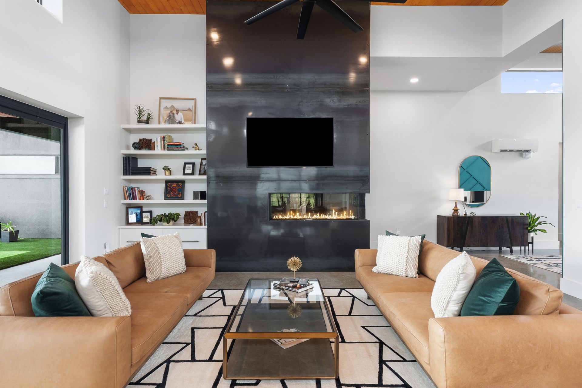 Modern living room with tan sofas, black fireplace wall, geometric rug, and high ceiling