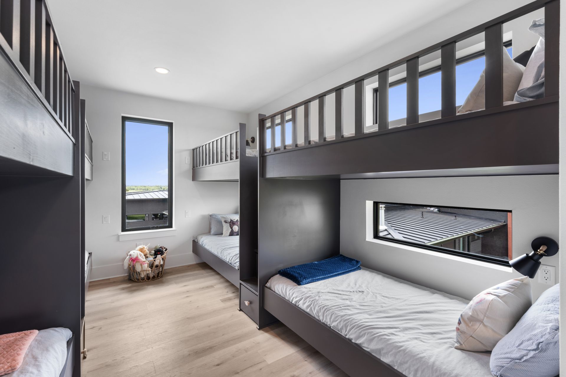 Modern bunk bedroom with two gray beds, large window, and light wood floor