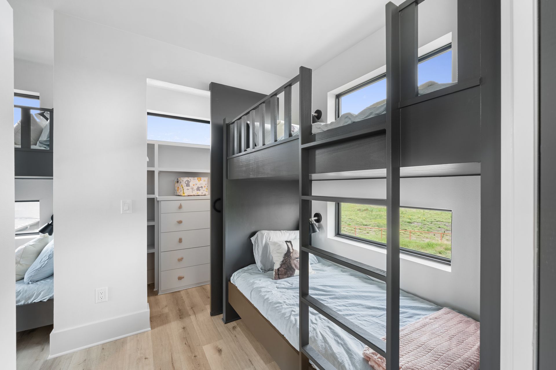 Small bunk room with black bunk beds, light wood floor, and a closet in the background