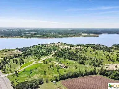 Aerial view of a green peninsula between a river and fields under a clear blue sky