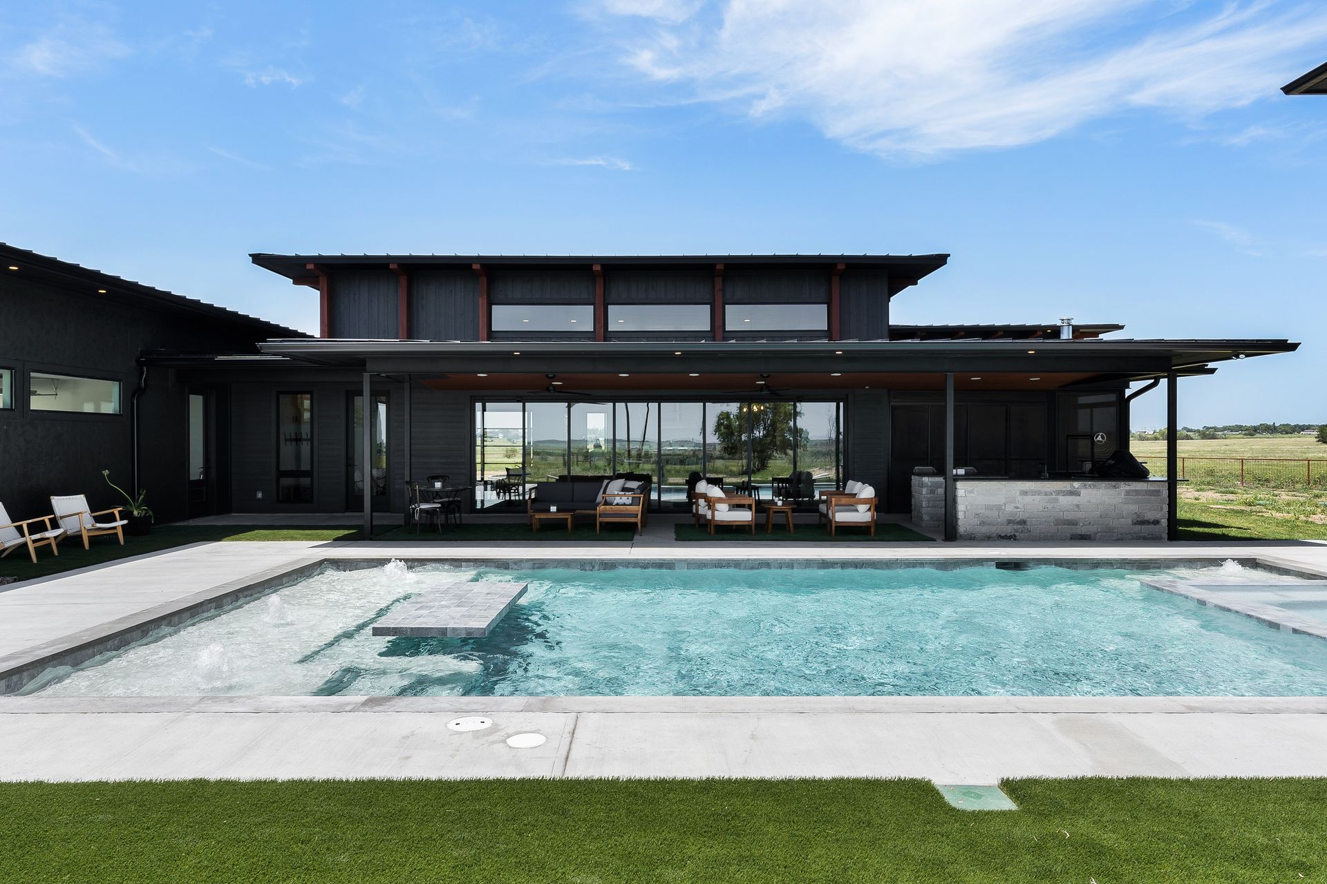 Modern house with a large backyard pool and patio under a clear blue sky