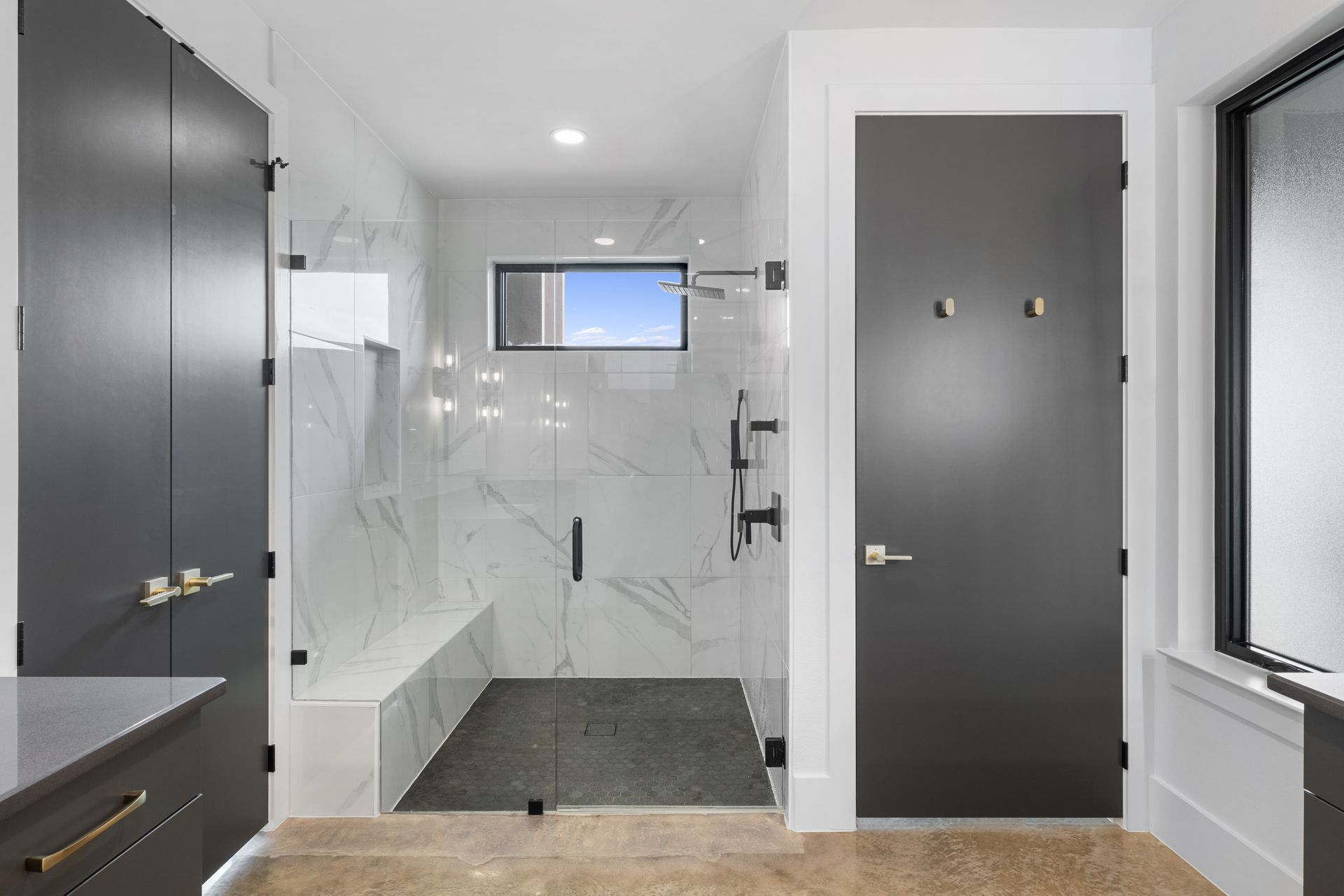Modern bathroom with gray doors, tiled walk-in shower, and a small window above the tub