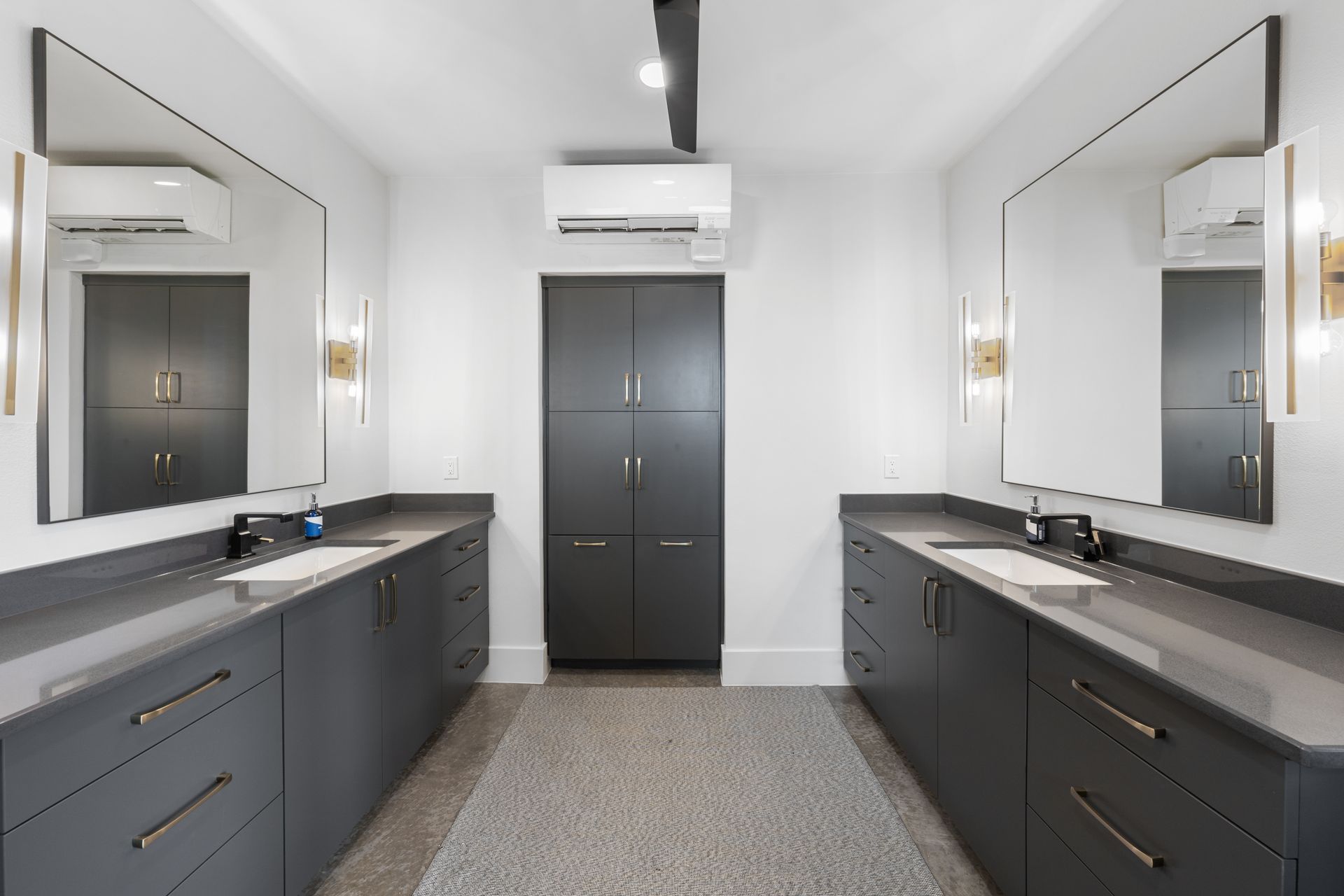 Modern gray double-sink bathroom with large mirrors and a central door