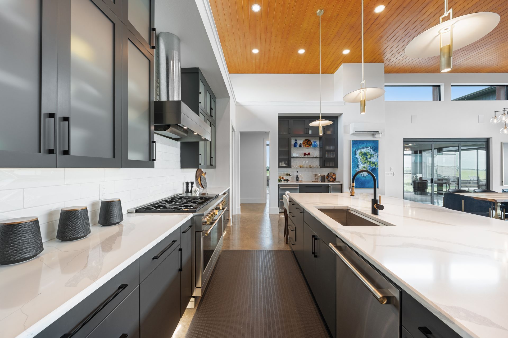 Modern kitchen with gray cabinets, white island, stainless appliances, and wood ceiling