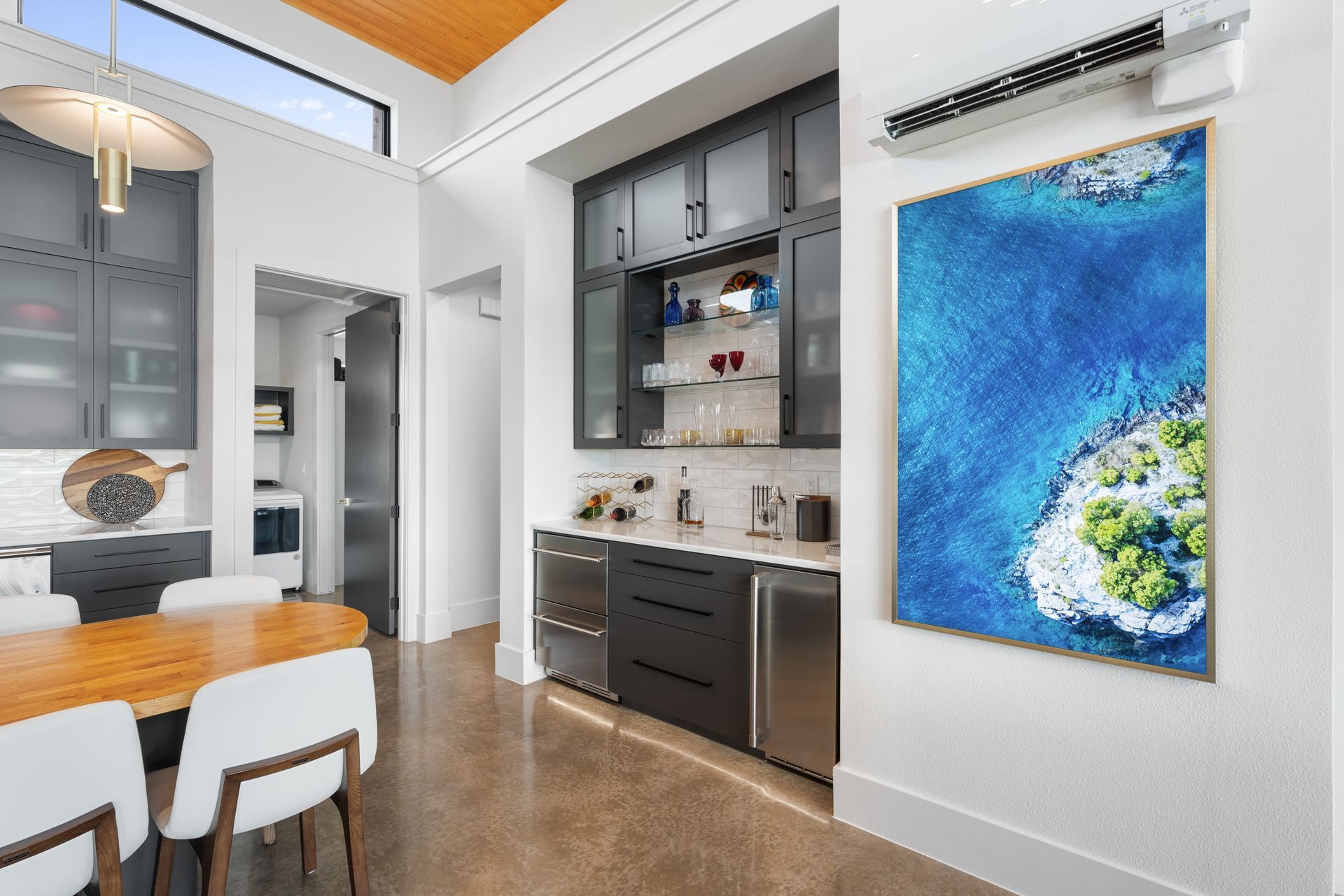 Modern dining area with white chairs, dark cabinets, and a large blue abstract wall painting