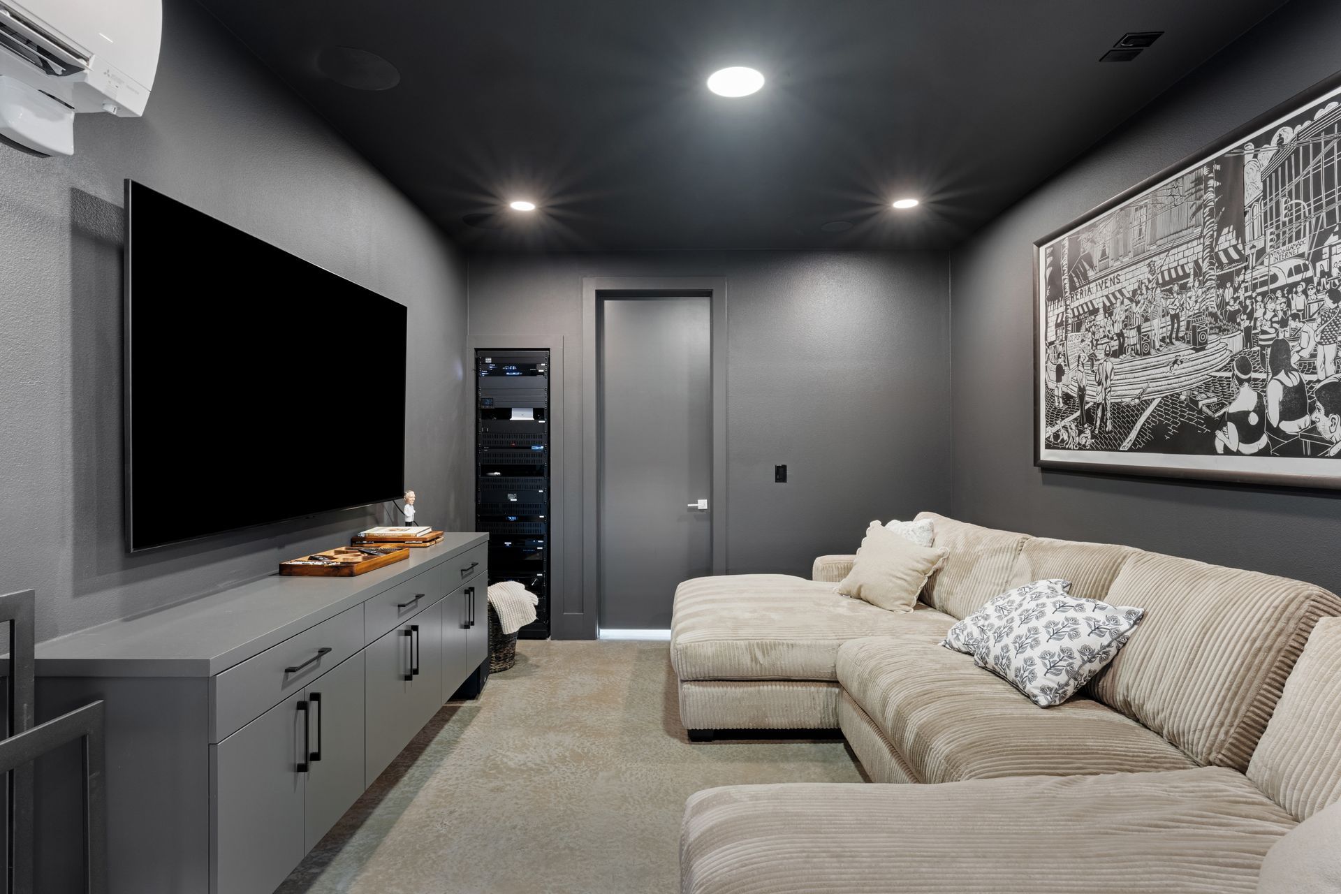 Modern gray media room with sectional sofa, wall-mounted TV, and large black-and-white city photo.