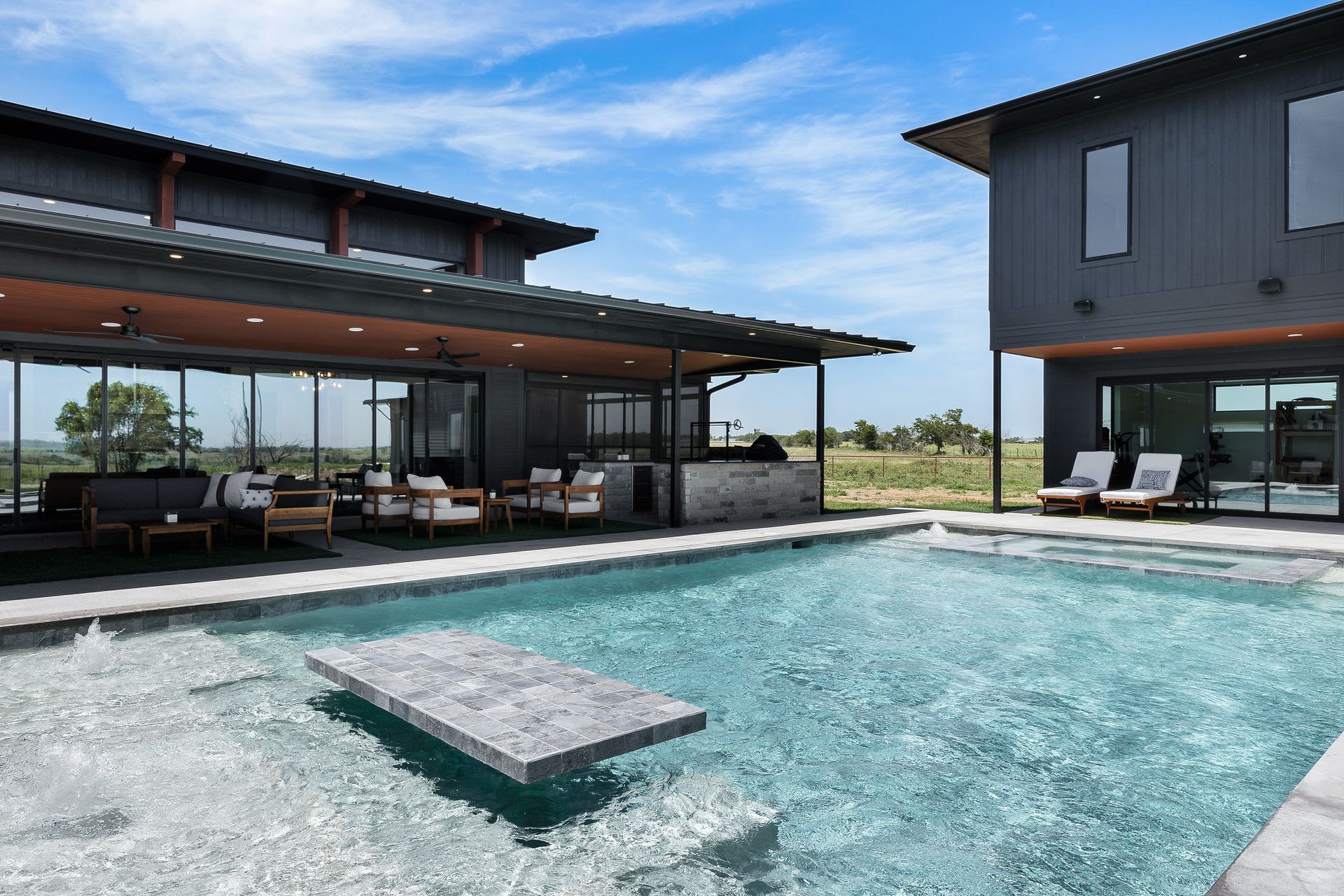 Modern house with a large pool and patio seating under a covered terrace