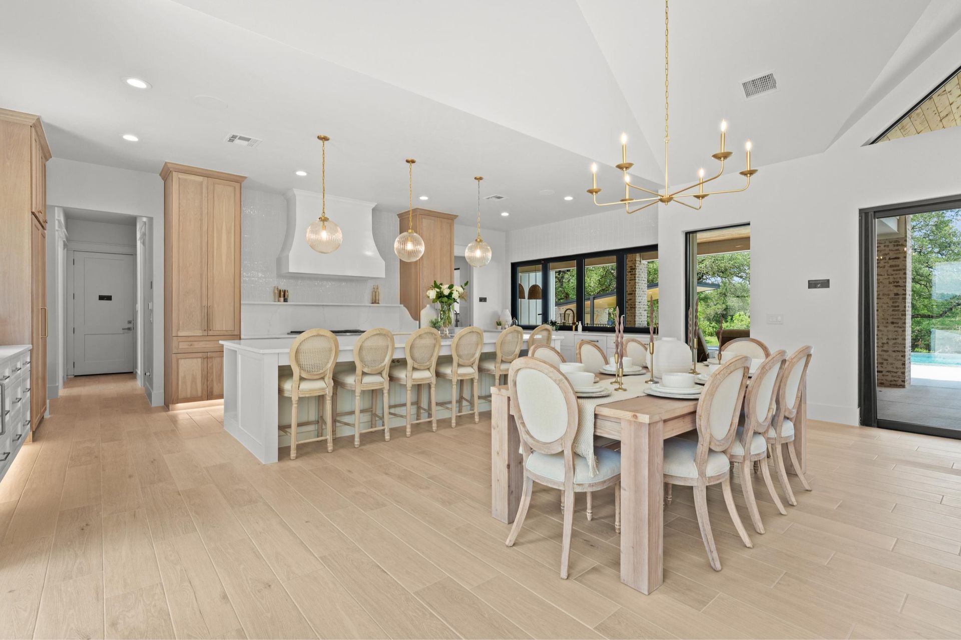 Bright open dining room and kitchen with white and wood furnishings, large windows, and a round table