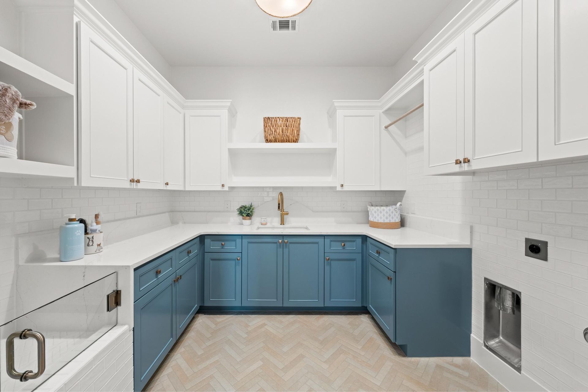 Bright white kitchen with blue lower cabinets, white upper cabinets, and a light tile floor.