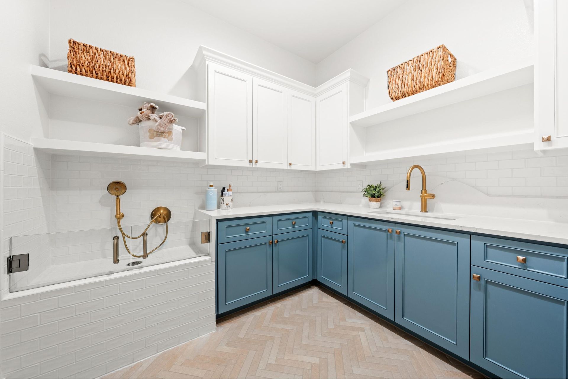 Bright modern laundry room with blue cabinets, white walls, gold fixtures, and open shelves
