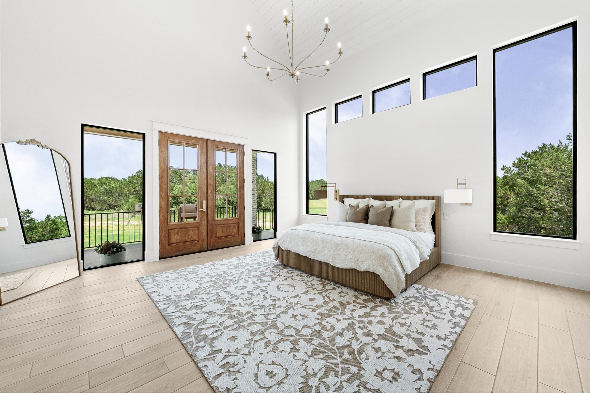 Bright minimalist bedroom with white walls, large windows, wood doors, and a patterned area rug