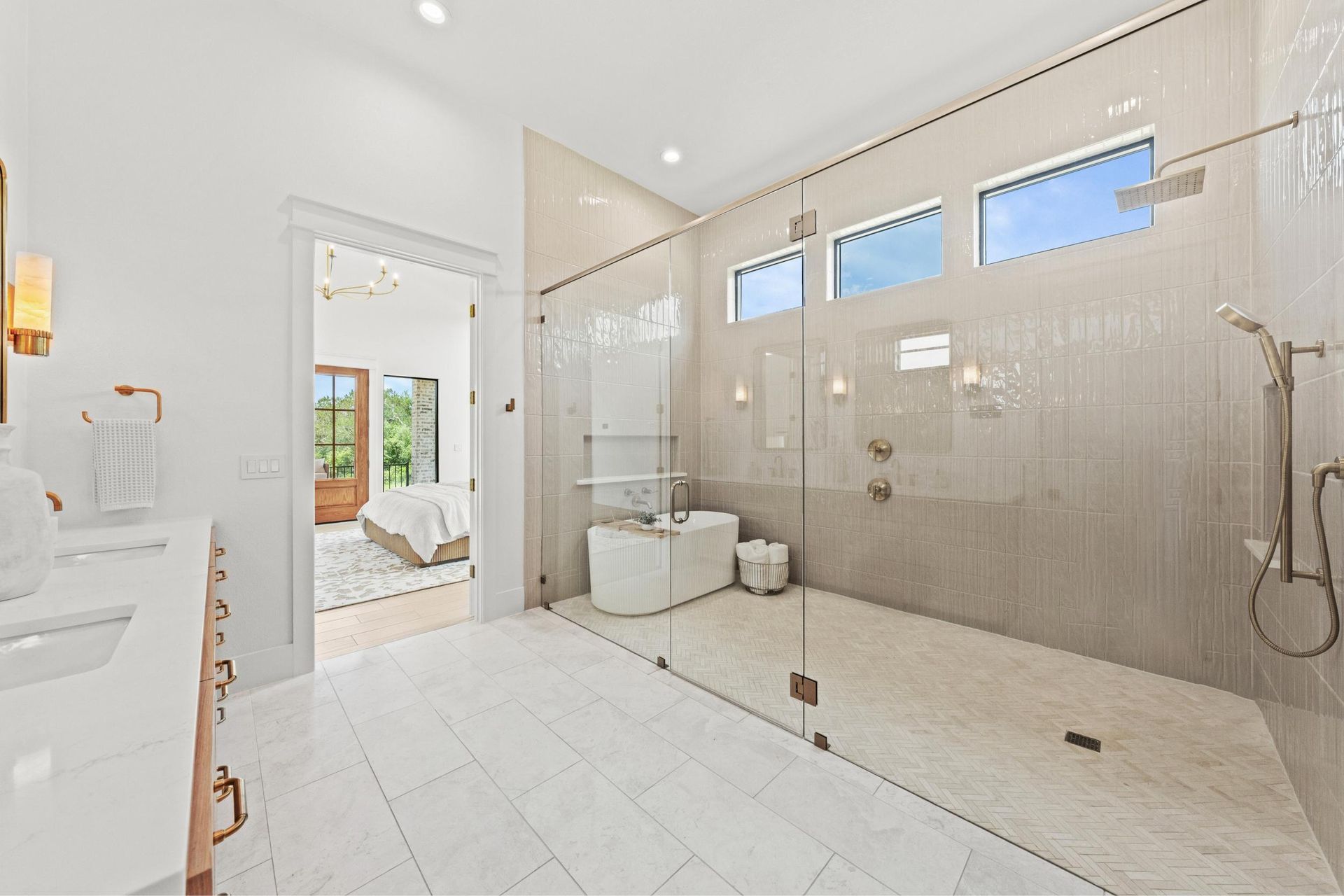 Spacious white bathroom with glass shower, double vanity, and bright windows