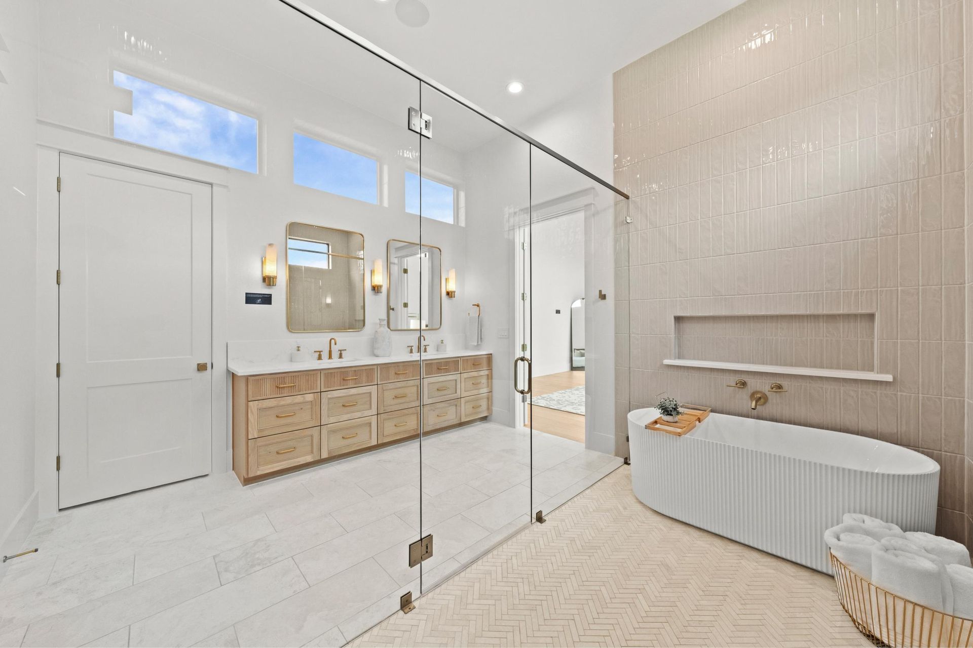 Bright modern bathroom with glass shower, double vanity, freestanding tub, and light tile walls