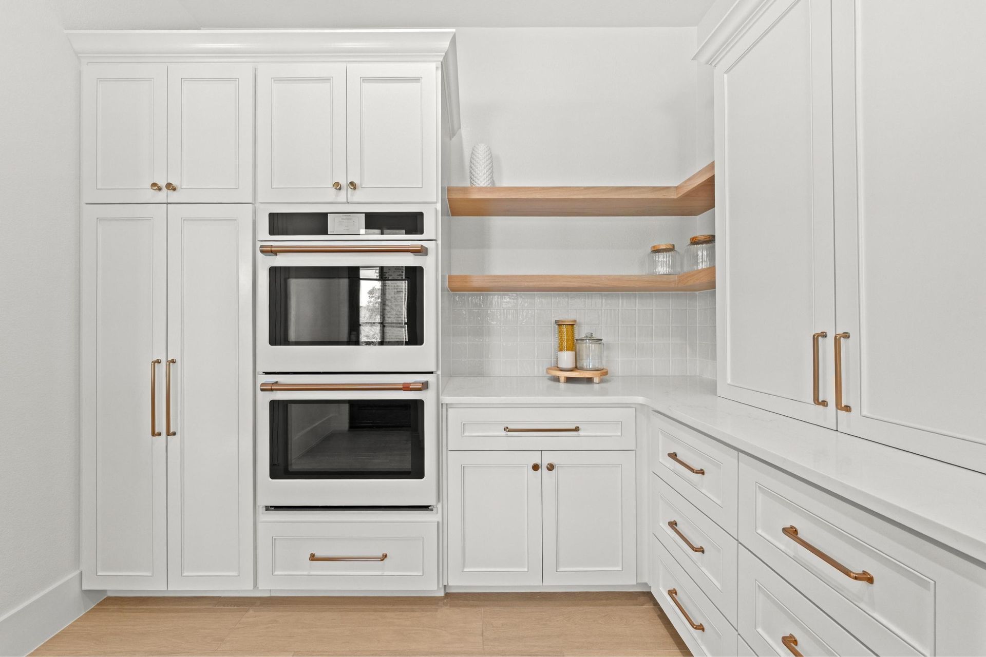 Bright white modern kitchen with built-in oven, open shelves, and gold hardware
