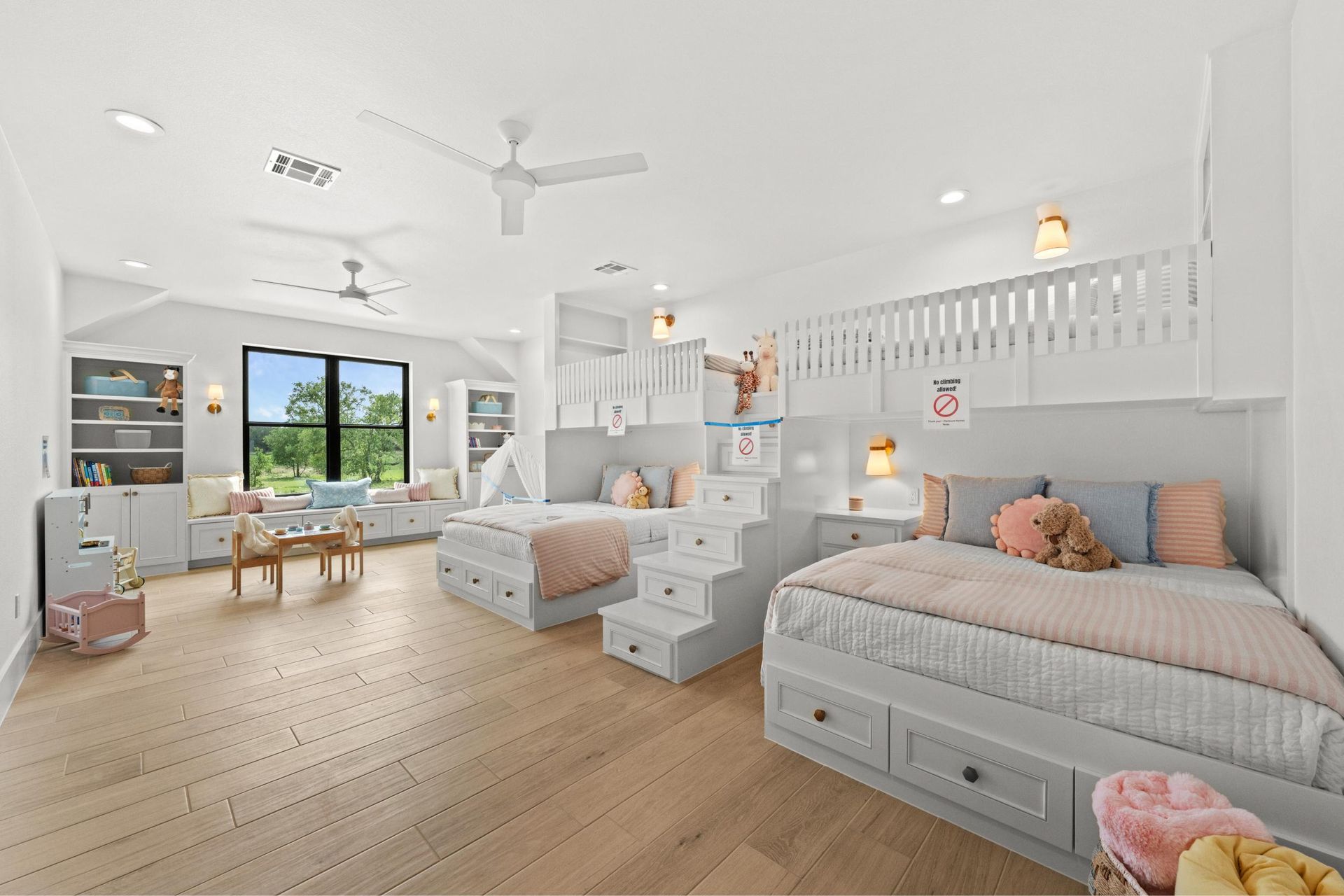 Bright airy child’s bedroom with twin beds, loft nook, play table, and wood floors