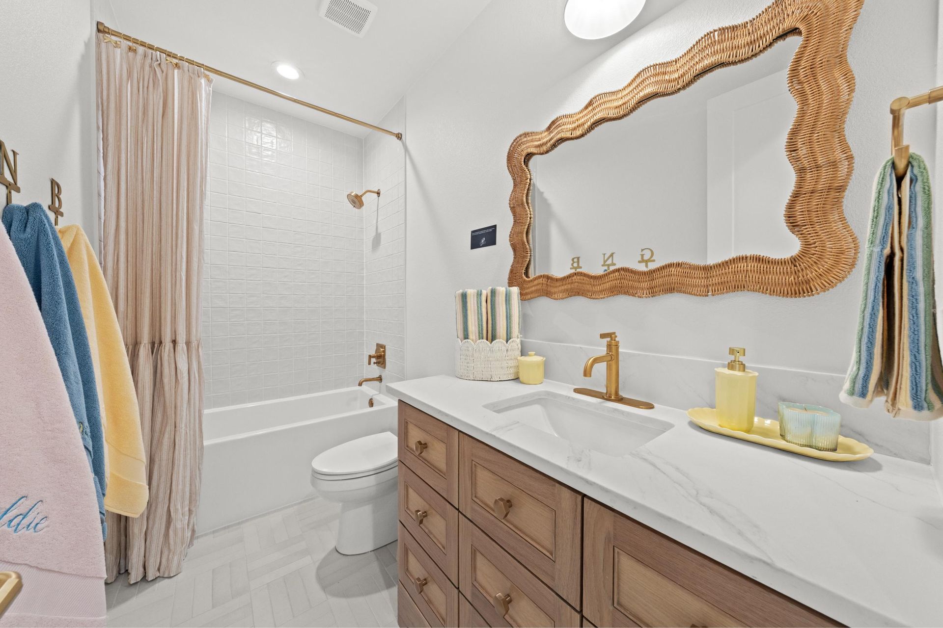 Bright bathroom with double vanity, gold mirror, white shower curtain, and towel racks