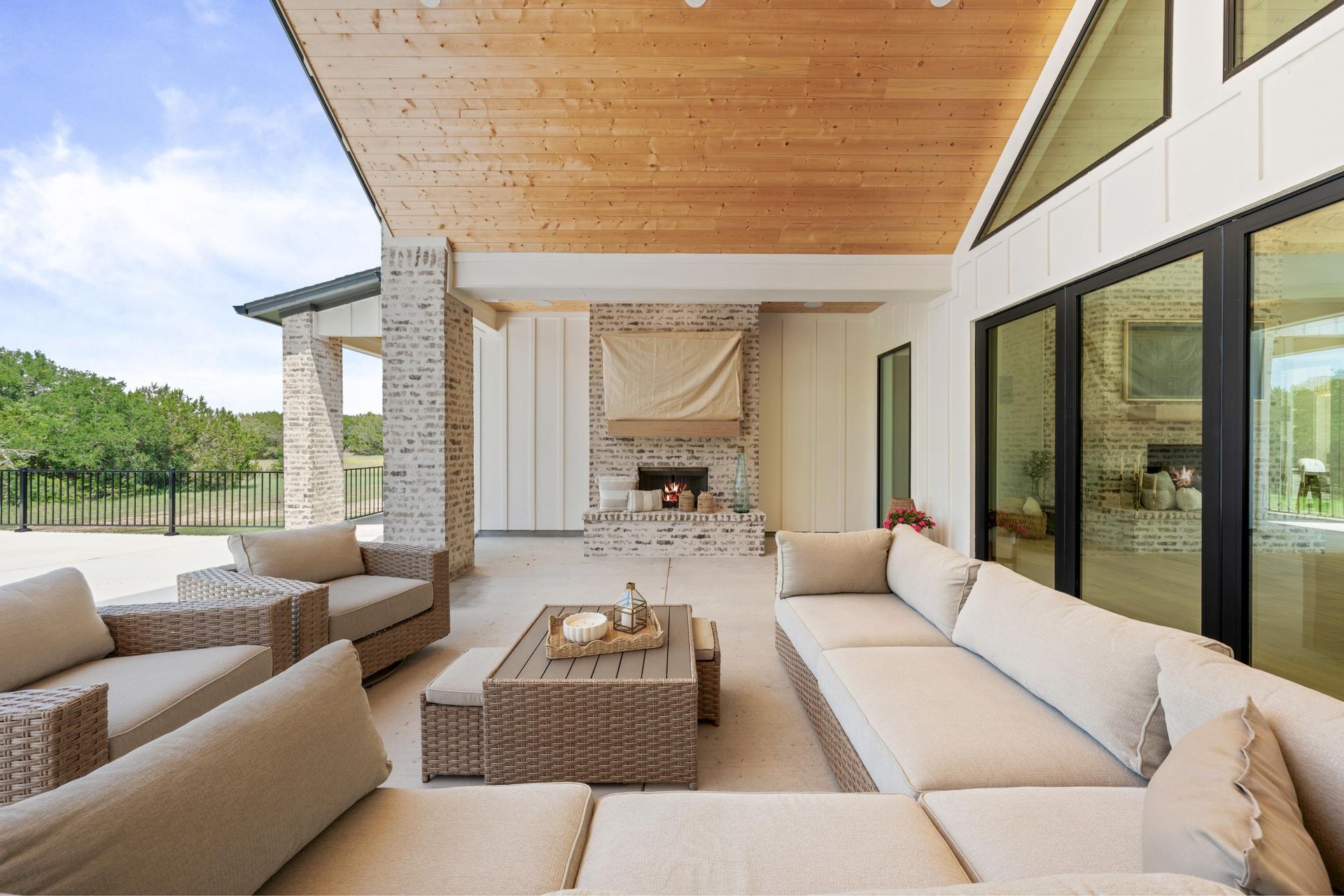 Modern covered patio with beige outdoor sofas, coffee table, and large sliding glass doors