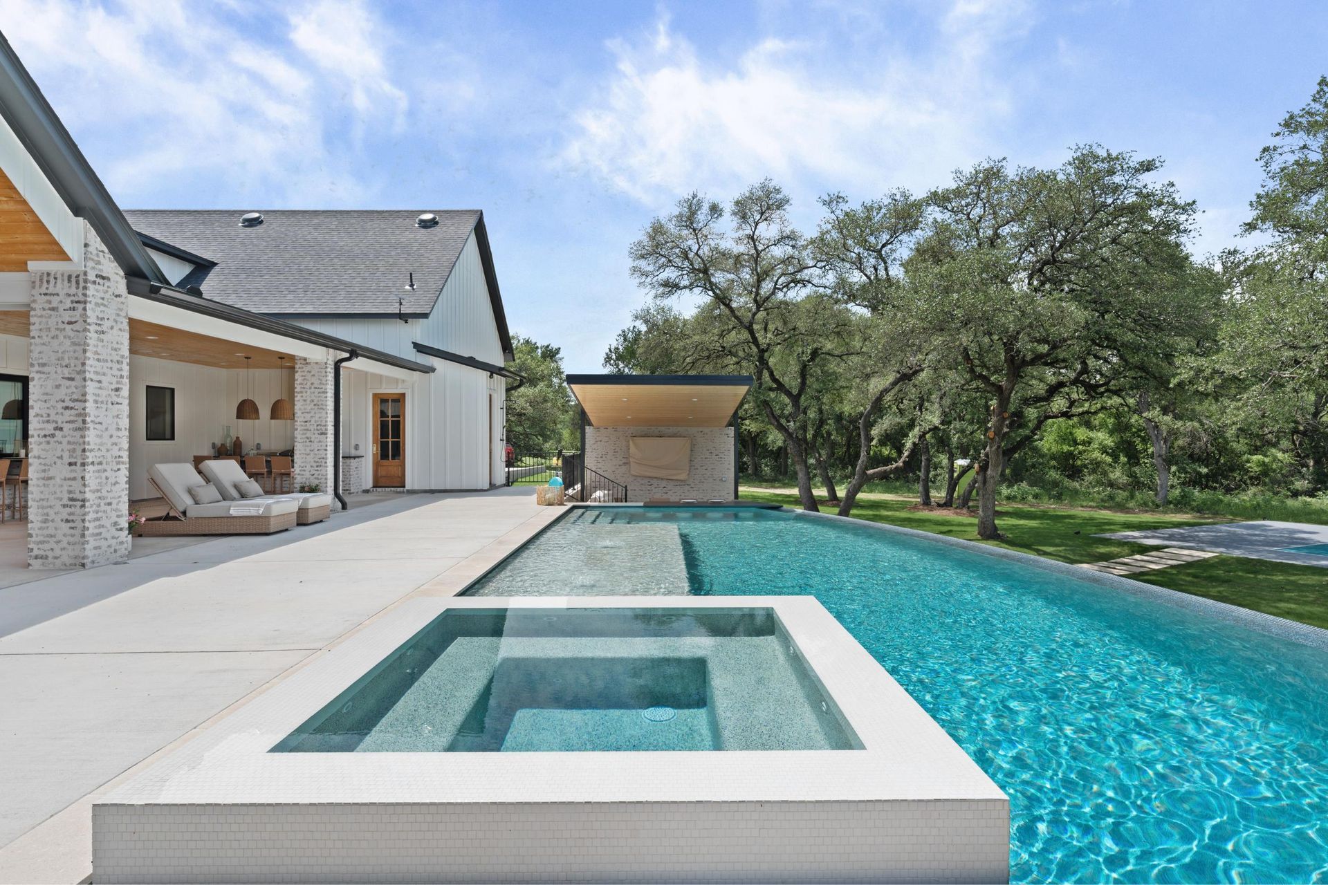 Modern backyard with turquoise pool, built-in spa, white patio, and a covered outdoor seating area