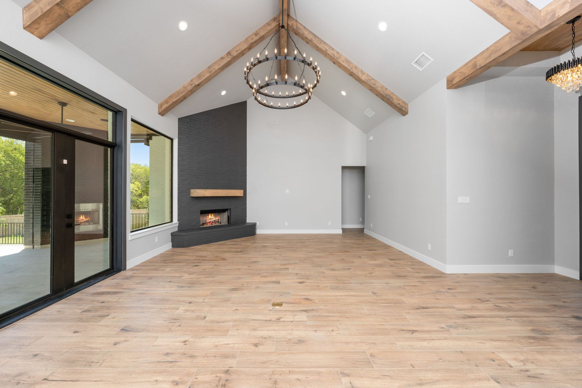 Spacious modern living room with vaulted ceilings, fireplace, wood floors, and large sliding glass doors