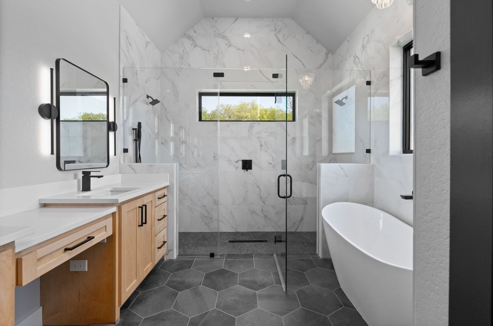 Modern bathroom with freestanding tub, glass shower, wood vanity, and hex tile floor
