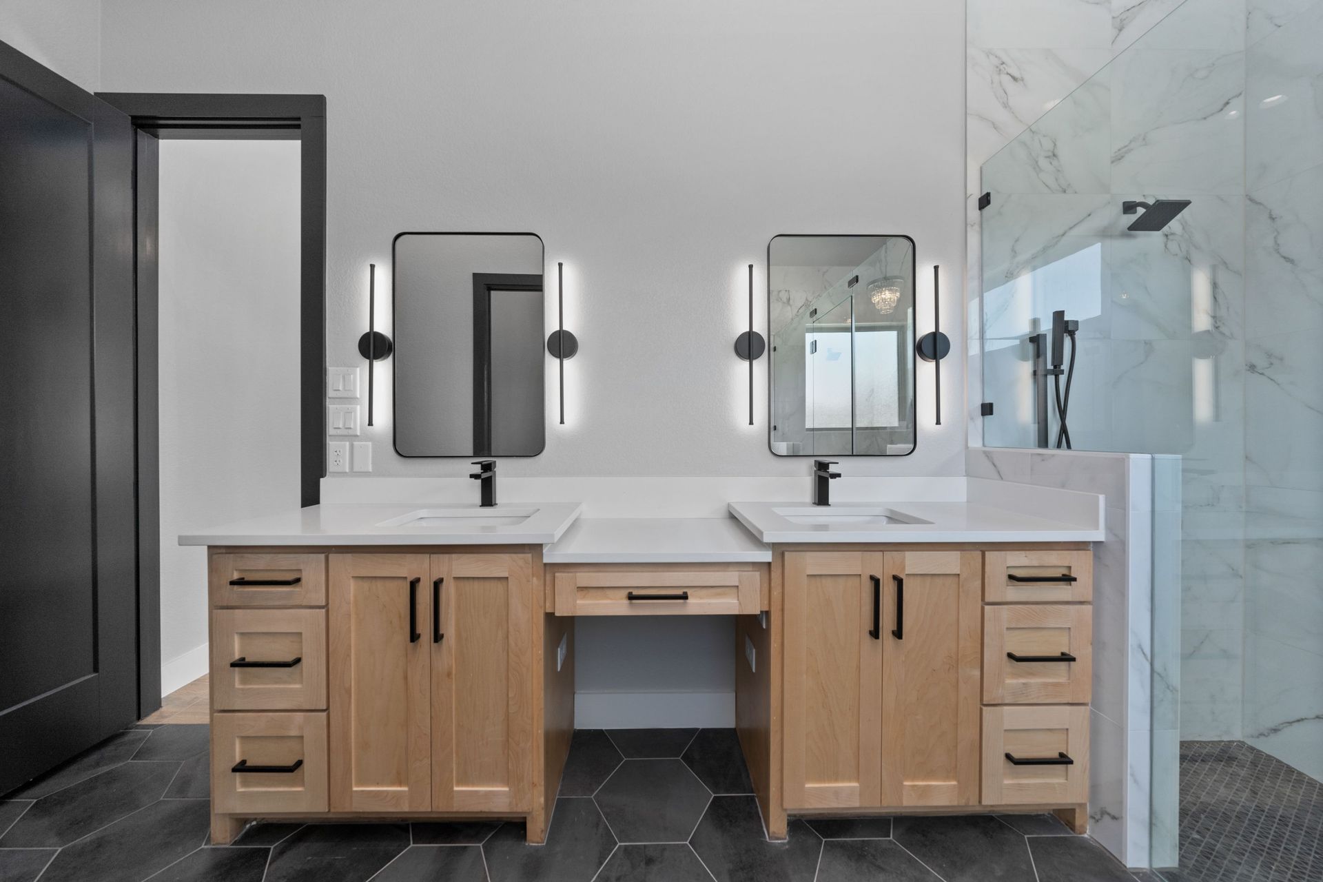 Modern bathroom with double wooden vanity, mirrors, wall sconces, and glass shower