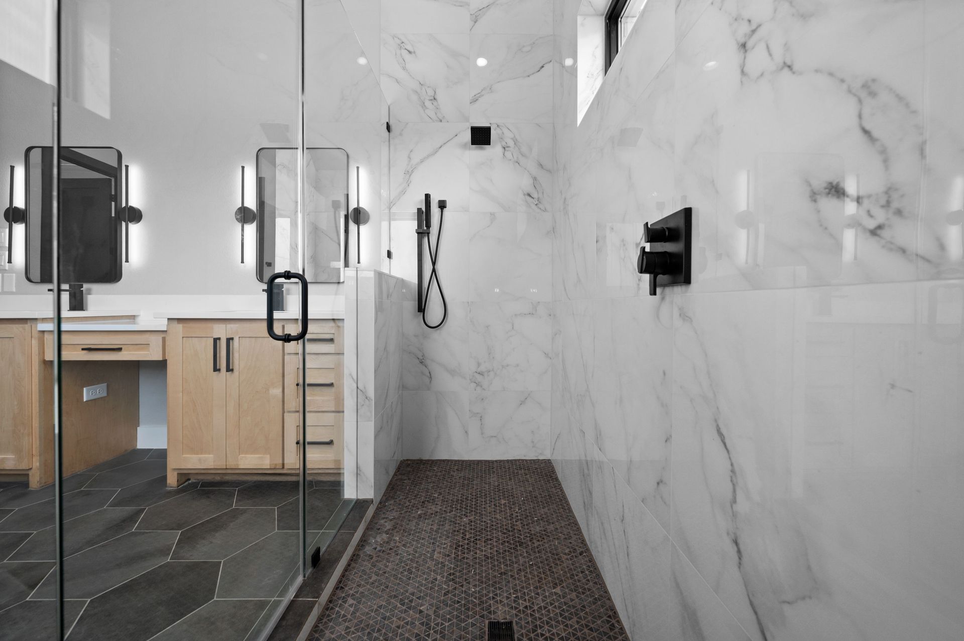 Modern bathroom with glass shower, wood vanity, and white marble-tile walls