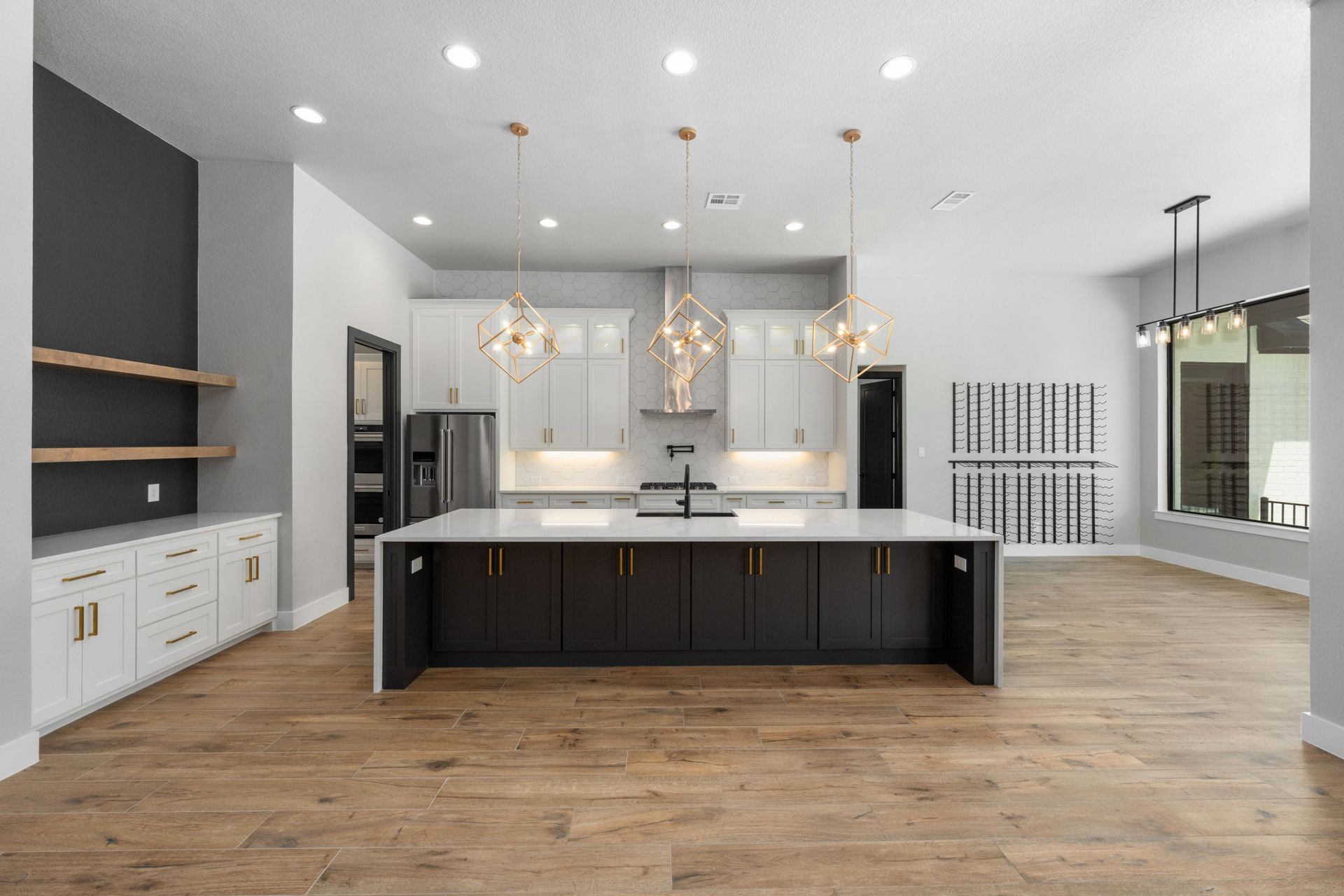 Modern open kitchen with large island, white cabinets, dark accents, and wood flooring
