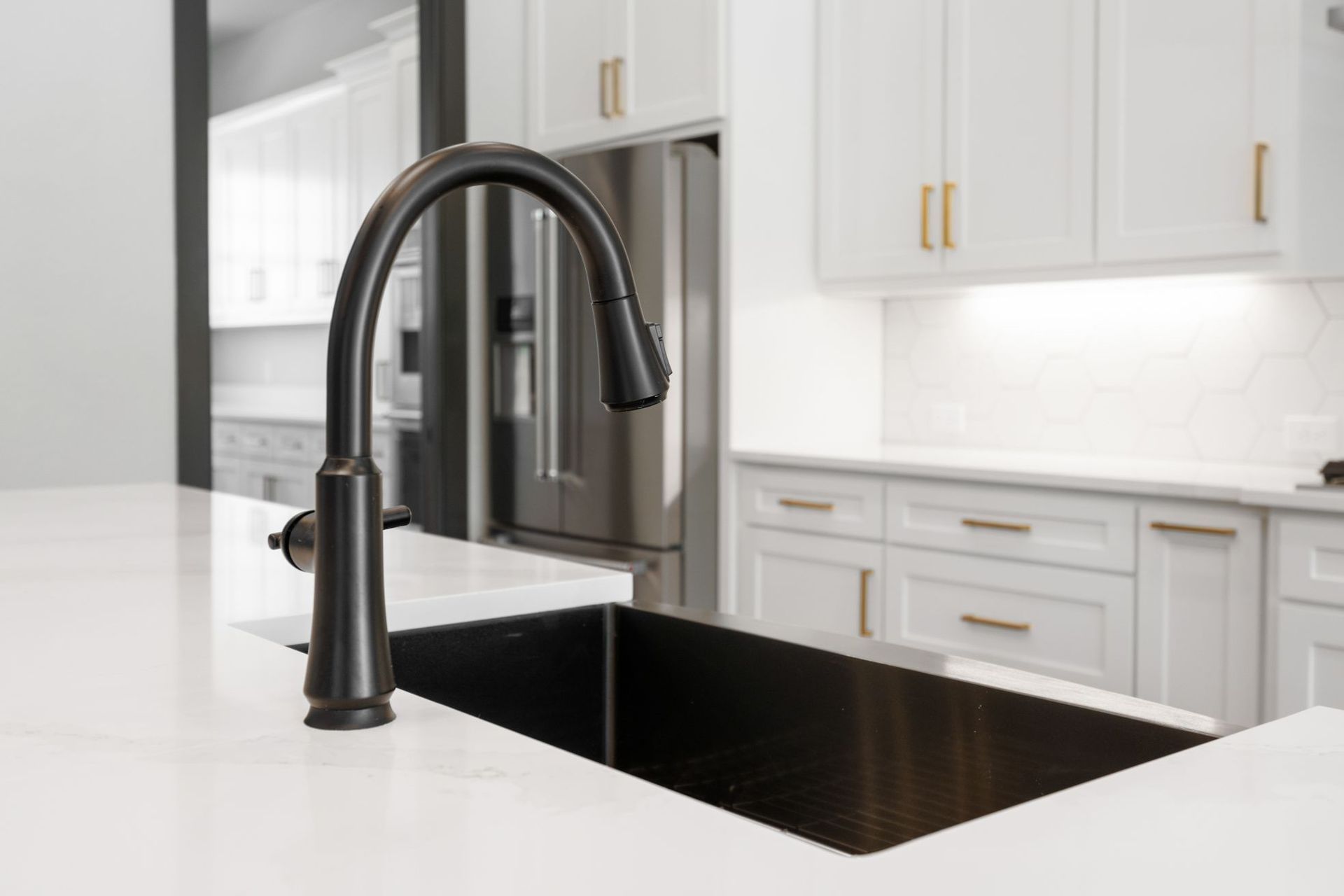 Modern white kitchen with a black farmhouse sink and matte black faucet