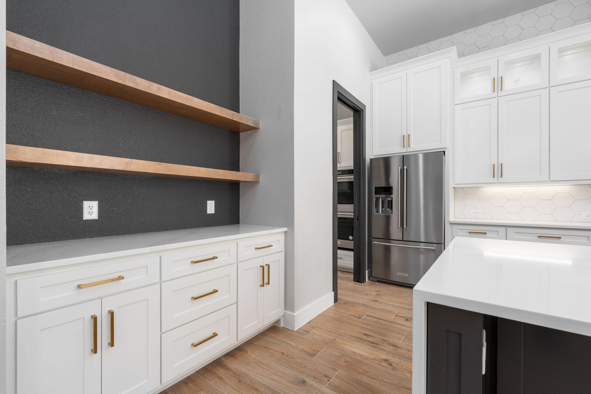 Modern kitchen with white cabinets, open wood shelves, stainless fridge, and wood floors
